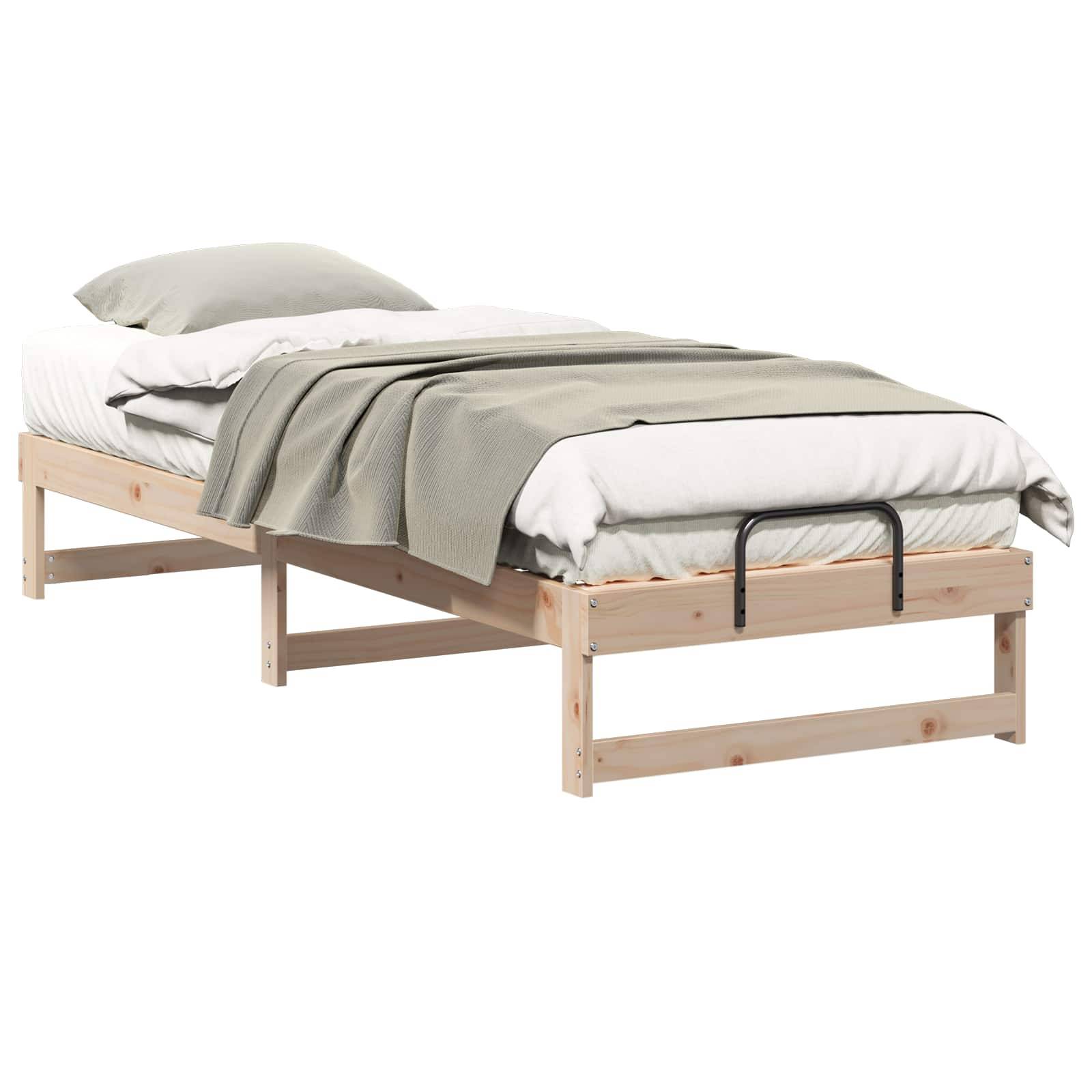 Ein Holz-Einzelbettgestell mit einer weißen Matratze und einer hellgrauen Decke, die darüber drapiert ist, mit einem Metallsicherheitsgeländer.