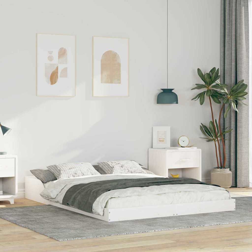 Ein minimalistisches Schlafzimmer mit einem weißen Bett, grauen Bettwäsche und zwei abstrakten Kunstwerken an der Wand. Eine Pflanze und eine Lampe stehen auf einem Nachttisch.