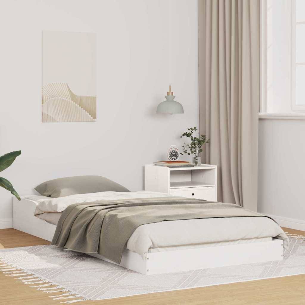 Ein minimalistisches Schlafzimmer zeigt ein niedriges, weißes Bett mit grauer Bettwäsche, einen kleinen Nachttisch mit einer Pflanze und eine Pendelleuchte.