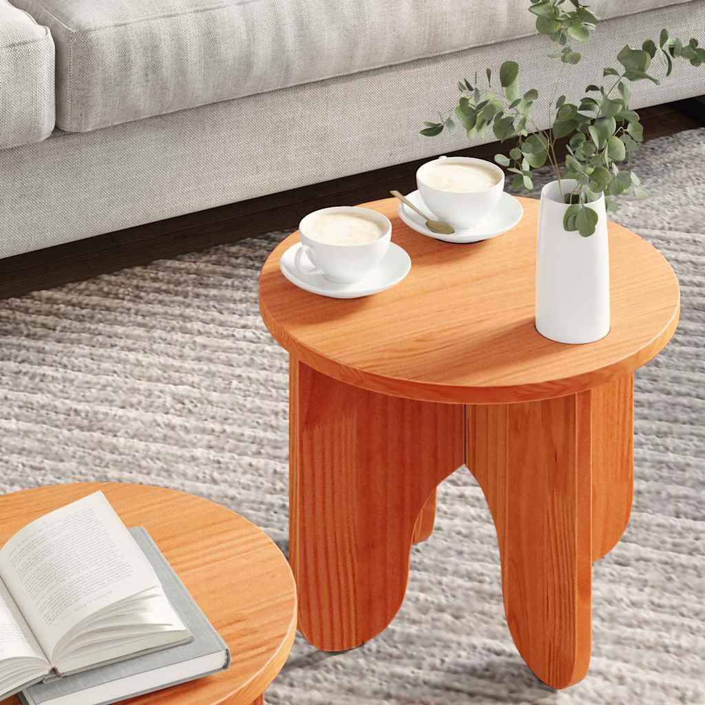 Ein gemütliches Wohnzimmer mit zwei kleinen Holztischen, auf denen jeweils weiße Tassen und Untertassen stehen. Auf einem Tisch befindet sich eine Vase mit Grünpflanzen; auf dem anderen liegt ein aufgeschlagenes Buch.