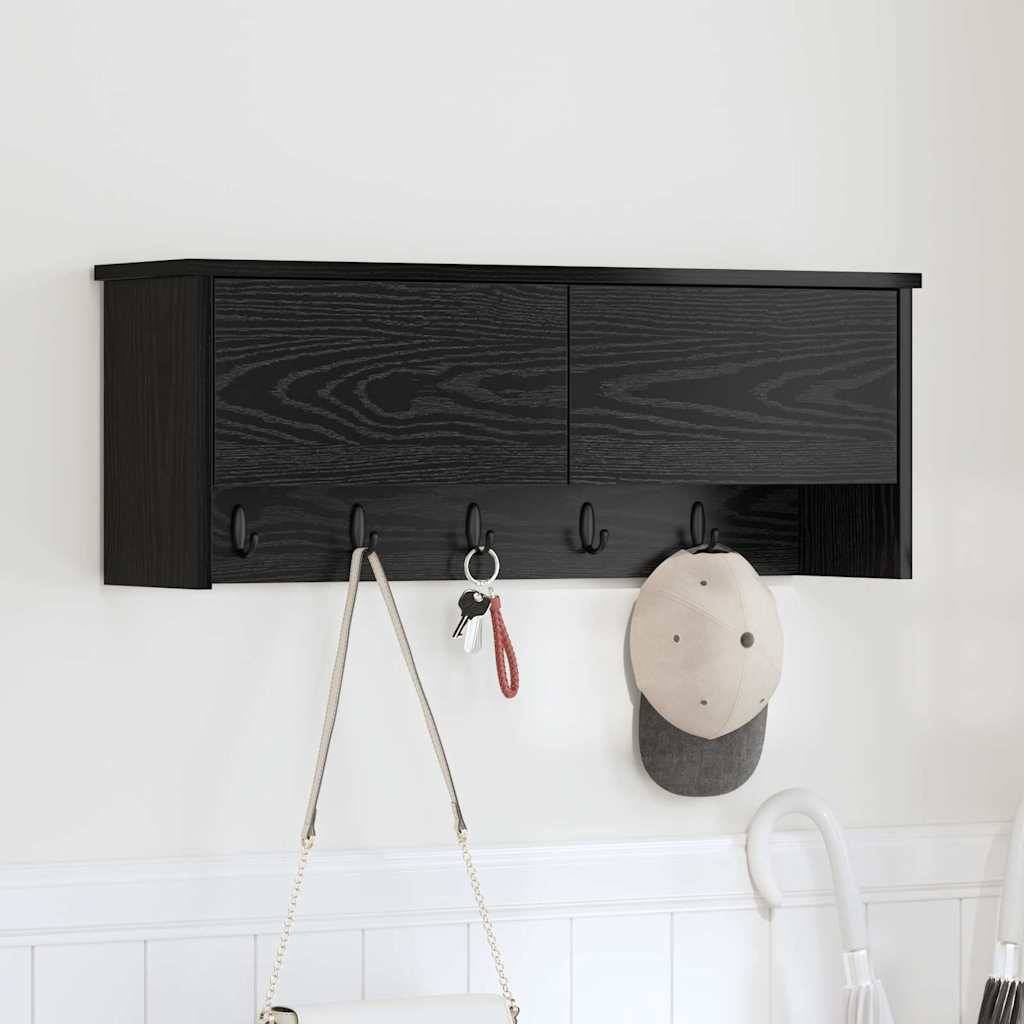 Ein schwarzes Holzwandregal mit vier Haken trägt eine Kappe und Schlüssel über einer weißen Vertäfelung in einem minimalistischen Innenraum.