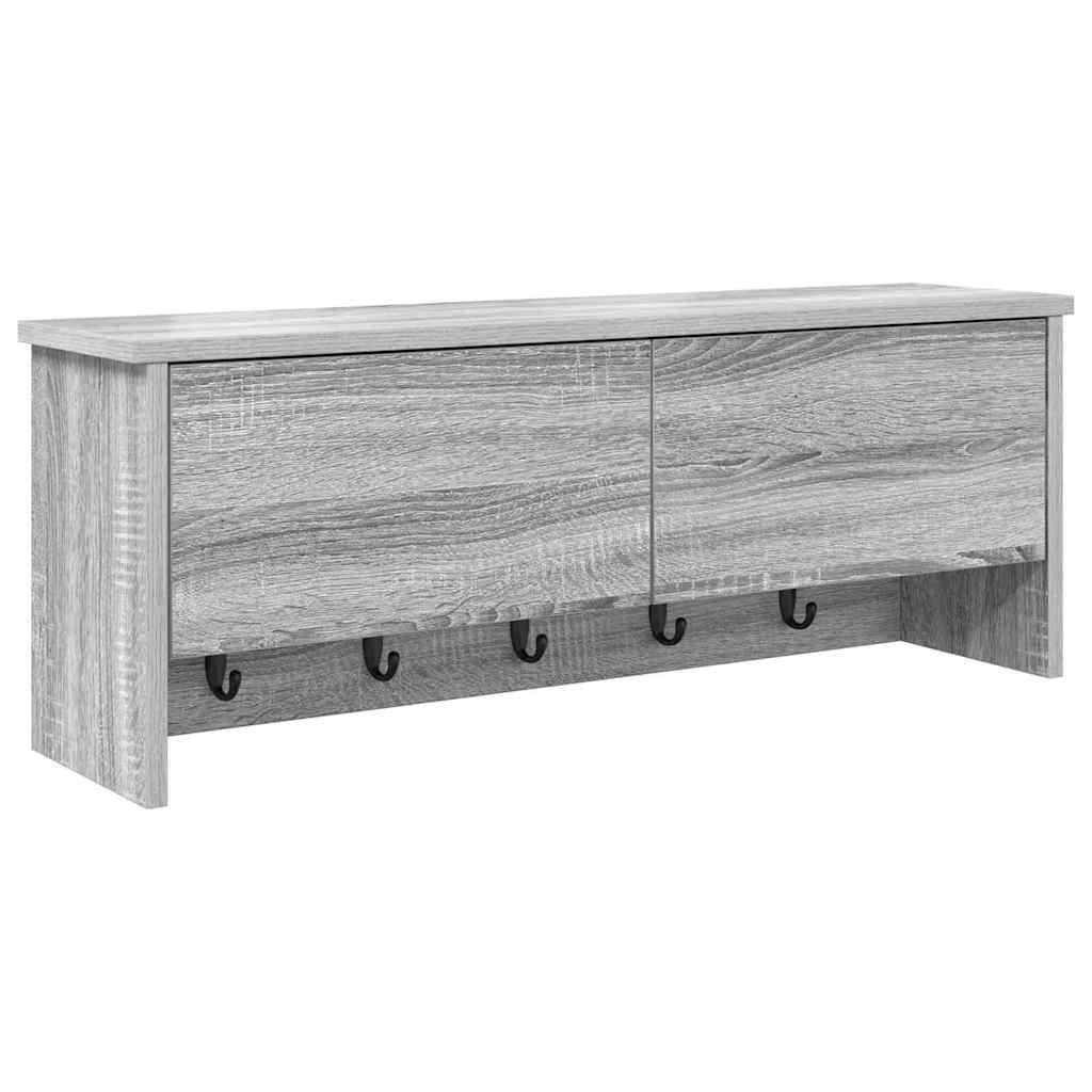 An der Wand befestigtes Holzregal in heller Graufarbe mit zwei Schranktüren oben und fünf schwarzen Haken darunter zum Aufhängen von Gegenständen.