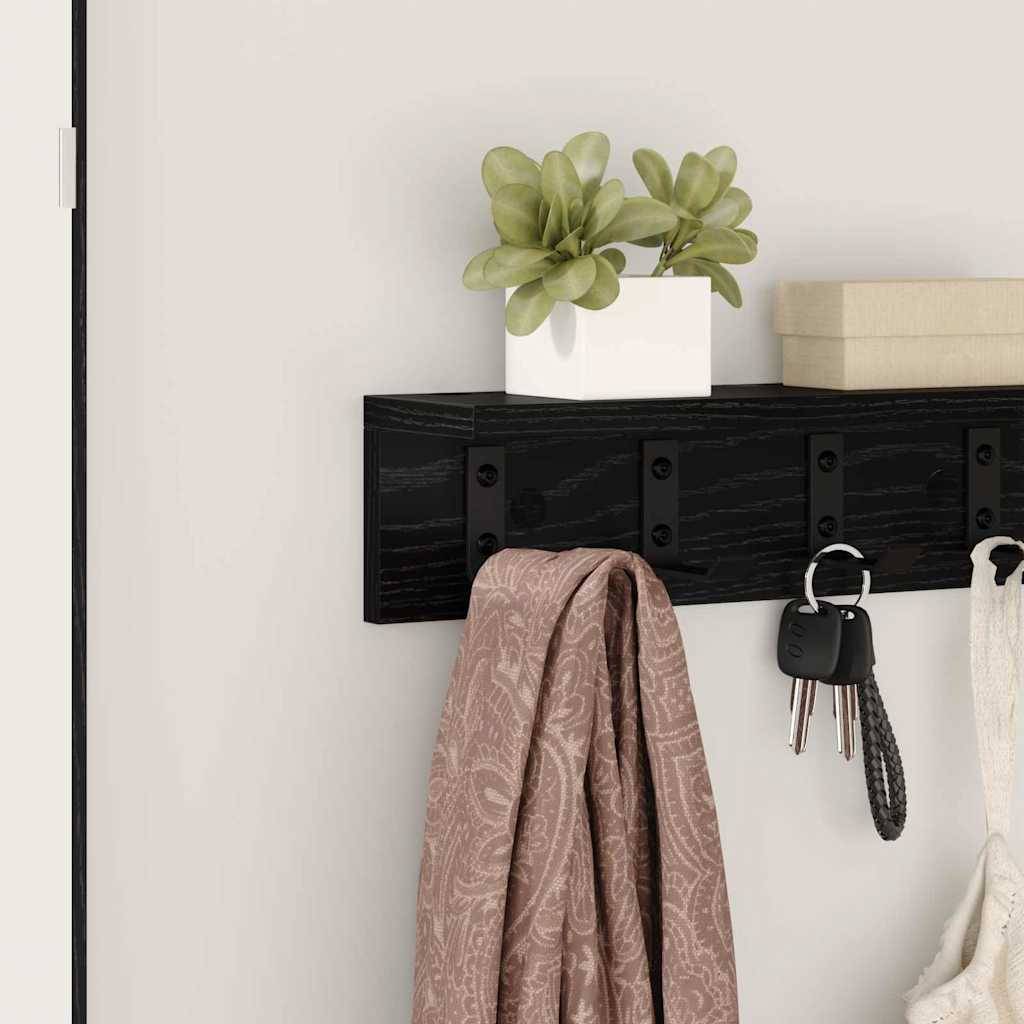Wandmontierte Garderobe mit vier Haken, an der eine Jacke, Schlüssel und eine Handtasche hängen. Darüber befindet sich eine kleine Pflanze und zwei geschlossene Bücher.