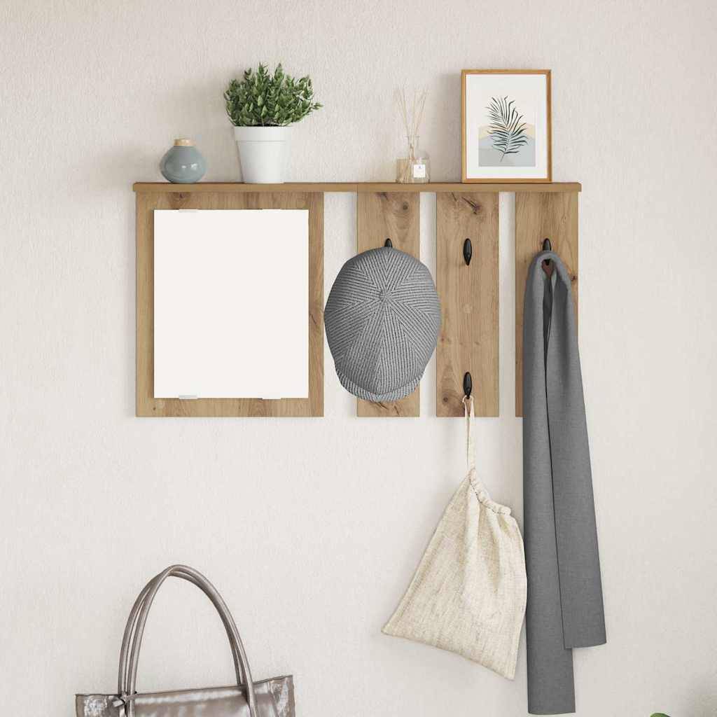 Hölzerne, wandmontierte Garderobe mit drei Haken, an denen ein grauer Hut, ein Schal und eine Tasche hängen. Darüber befinden sich ein Spiegel, eine Pflanze und ein gerahmter Druck.