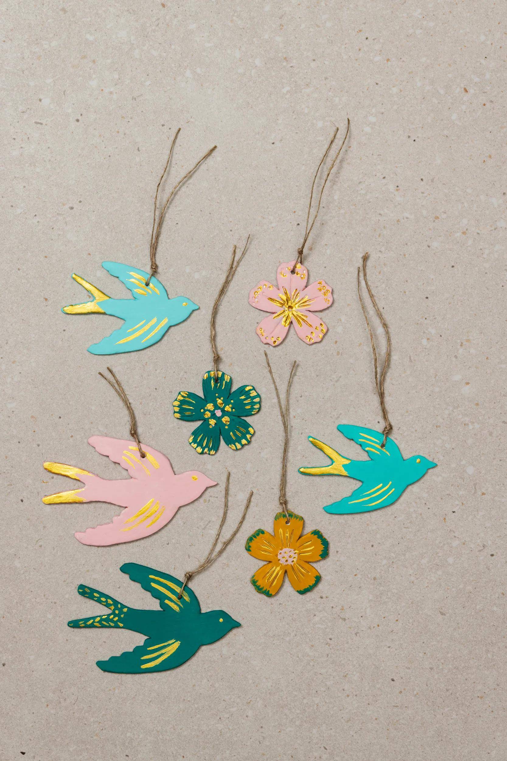 Sortierte hängende Vogel- und Blumenverzierungen in Pastell- und Blaugrüntönen, auf neutralem Hintergrund präsentiert.