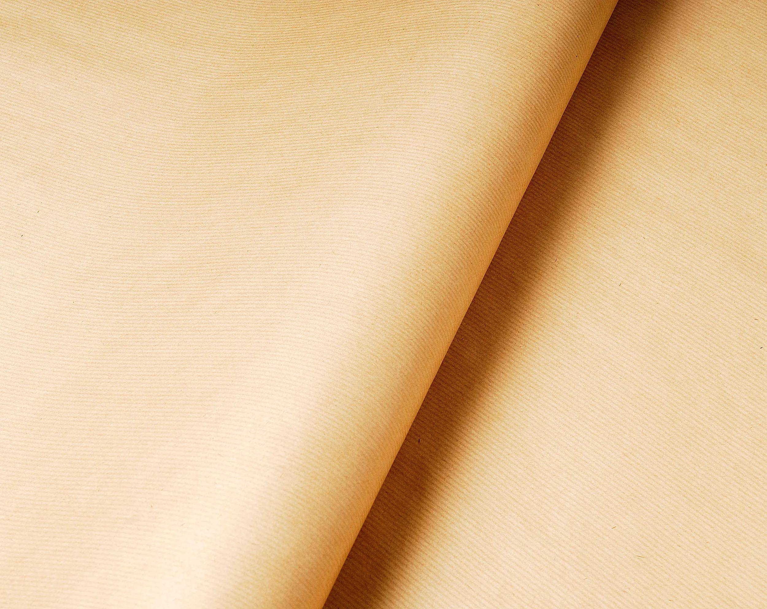 Eine Nahaufnahme eines glatten, creme­farbenen Papiers mit einer leicht gekrümmten Kante, die seine Textur und Einfachheit hervorhebt.