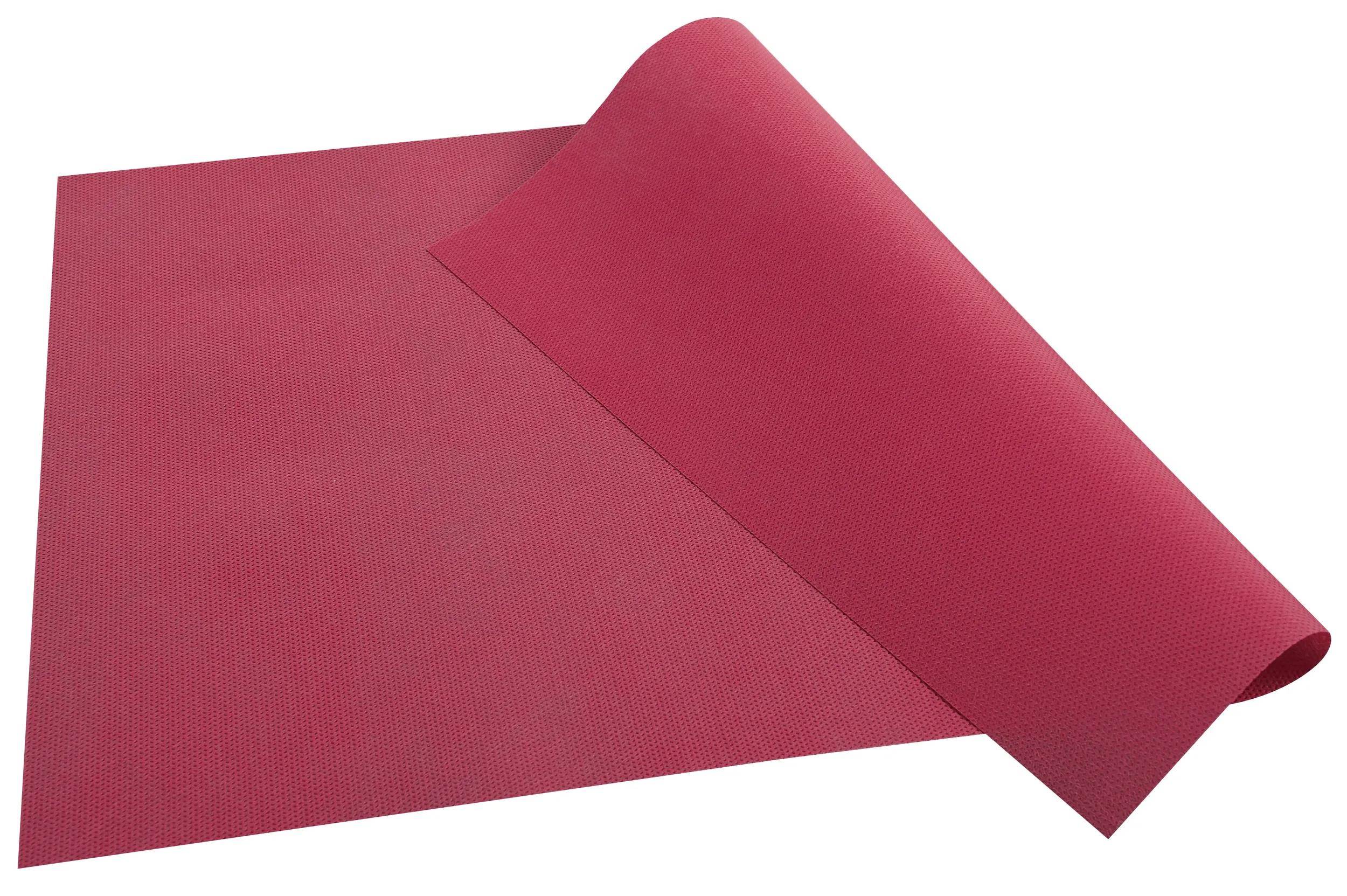 Eine ausgerollte rote Yogamatte, teilweise aufgerollt, ruht auf einer flachen Oberfläche.