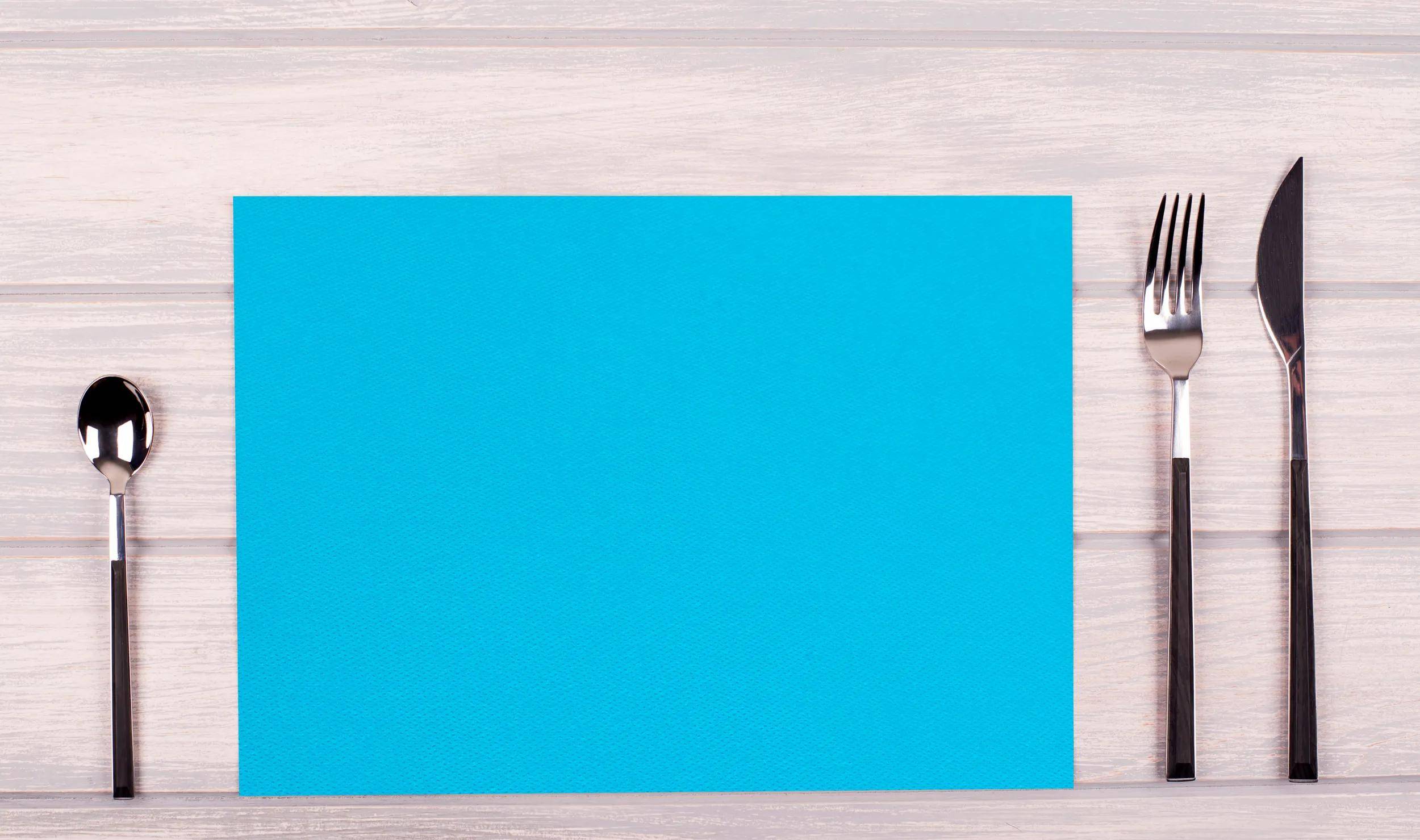 Ein einfaches, leuchtendes blaues Blatt Papier liegt auf einer Holzoberfläche.