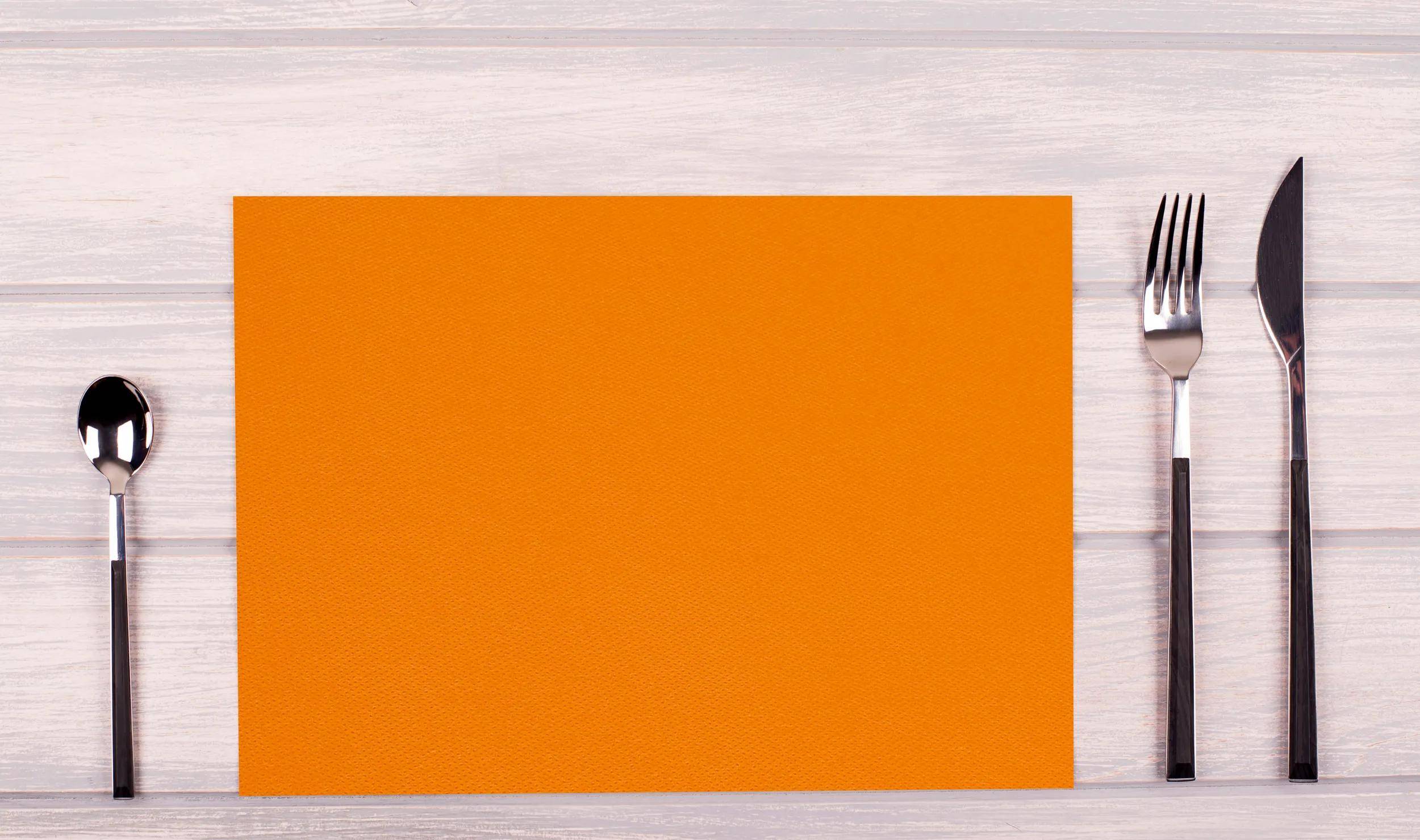 Ein orange strukturiertes Papier auf einer hellen Holzoberfläche.