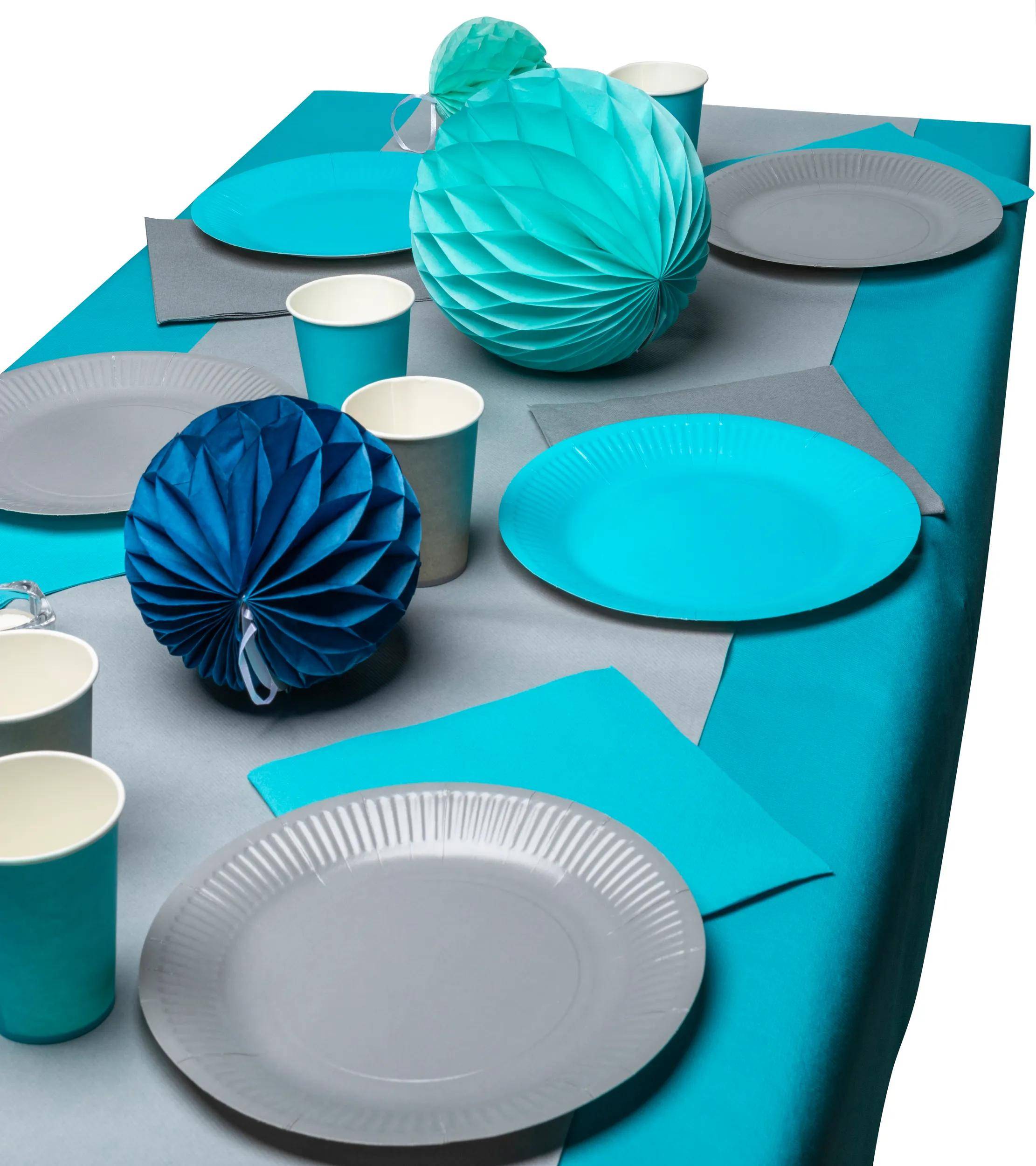 Ein Tisch mit türkisfarbenen und grauen Tellern, Tassen und Papierdeko ordentlich arrangiert für eine Partyeinstellung.
