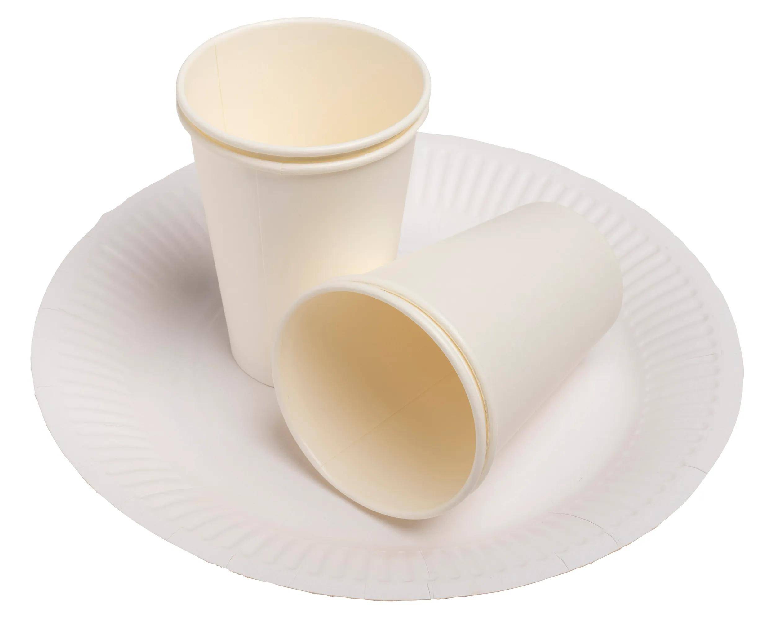Zwei weiße Papiertassen, eine aufrecht stehend und eine auf ihrer Seite liegend, werden auf einem weißen Papierteller vor einem neutralen Hintergrund platziert.
