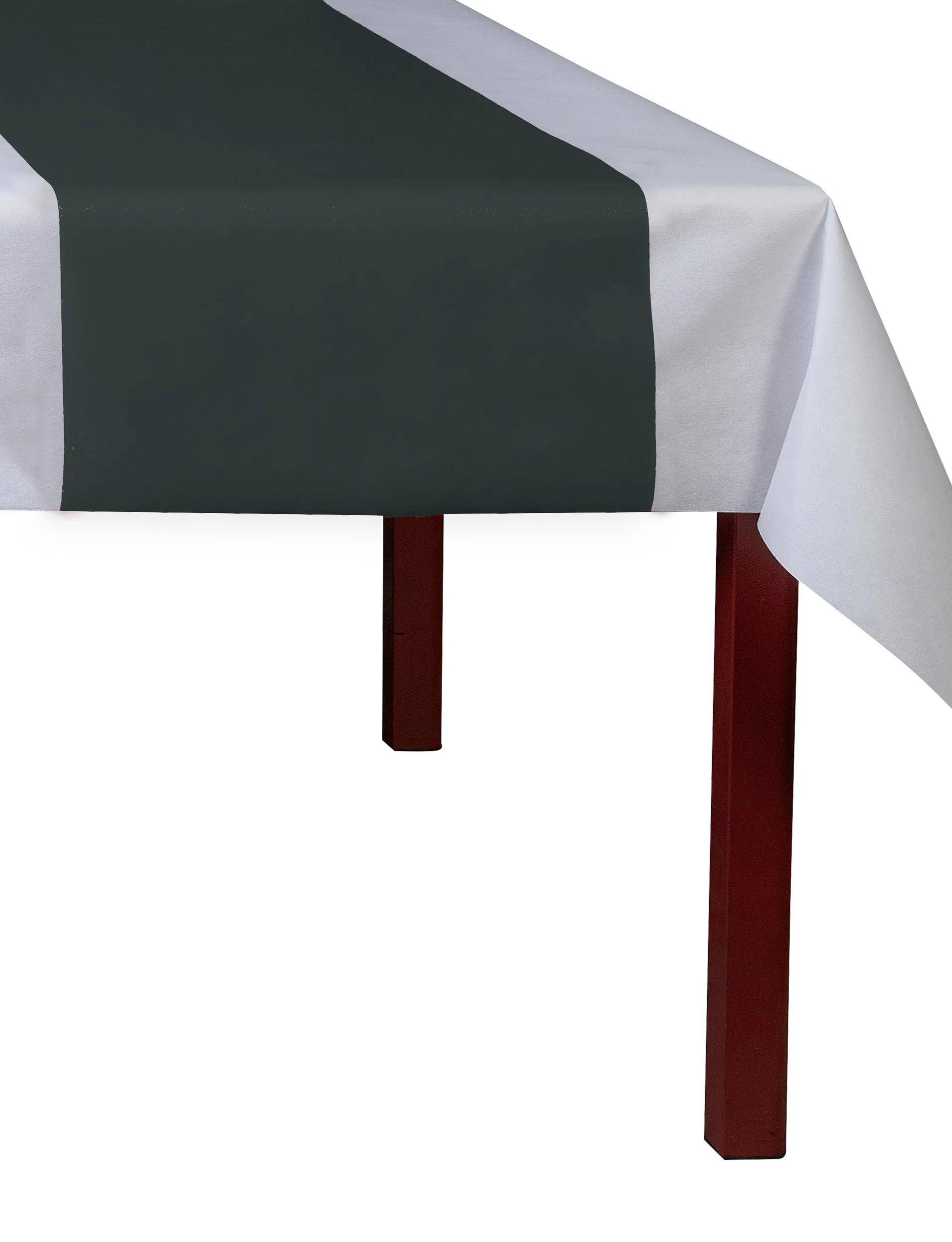 Ein Tisch ist mit einem weißen Tuch und einem dunkelgrünen Tischläufer bedeckt, vor einem einfachen weißen Hintergrund angeordnet.