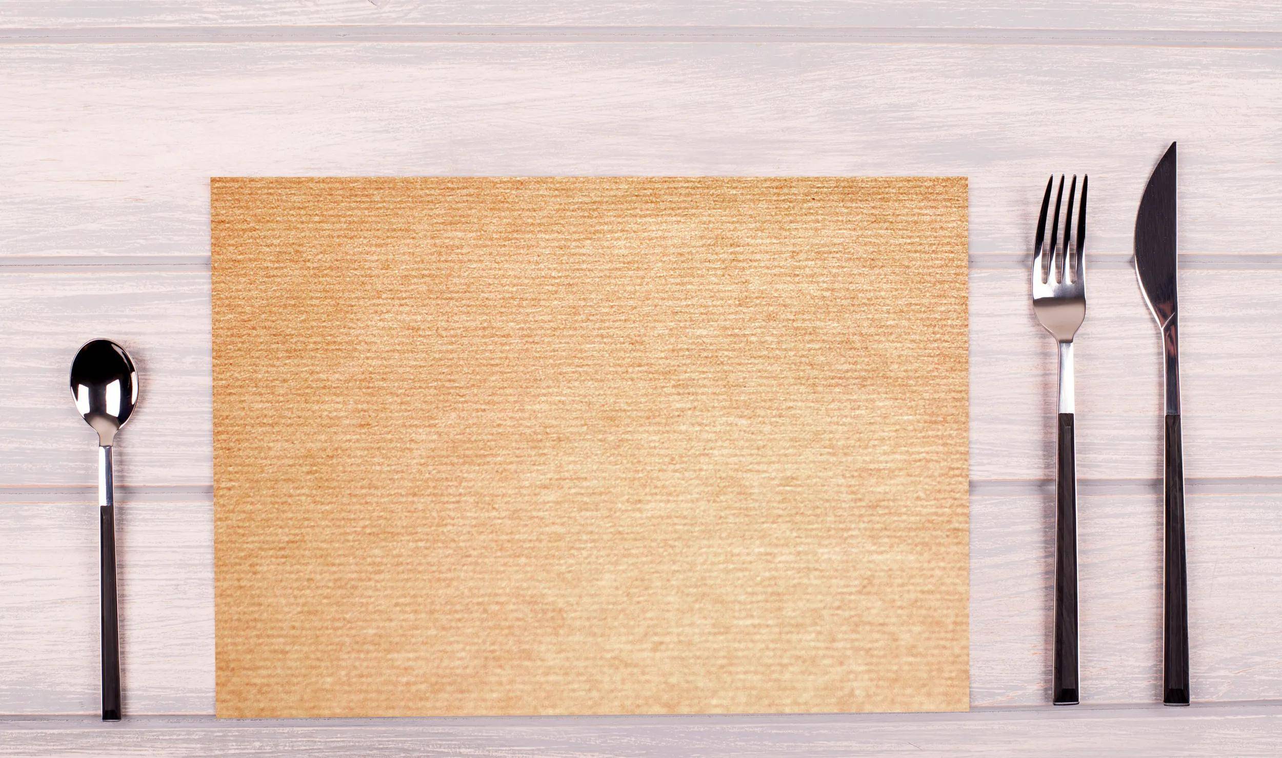 Ein Blatt hellbraunes strukturiertes Papier, das flach auf einer Holzoberfläche liegt.