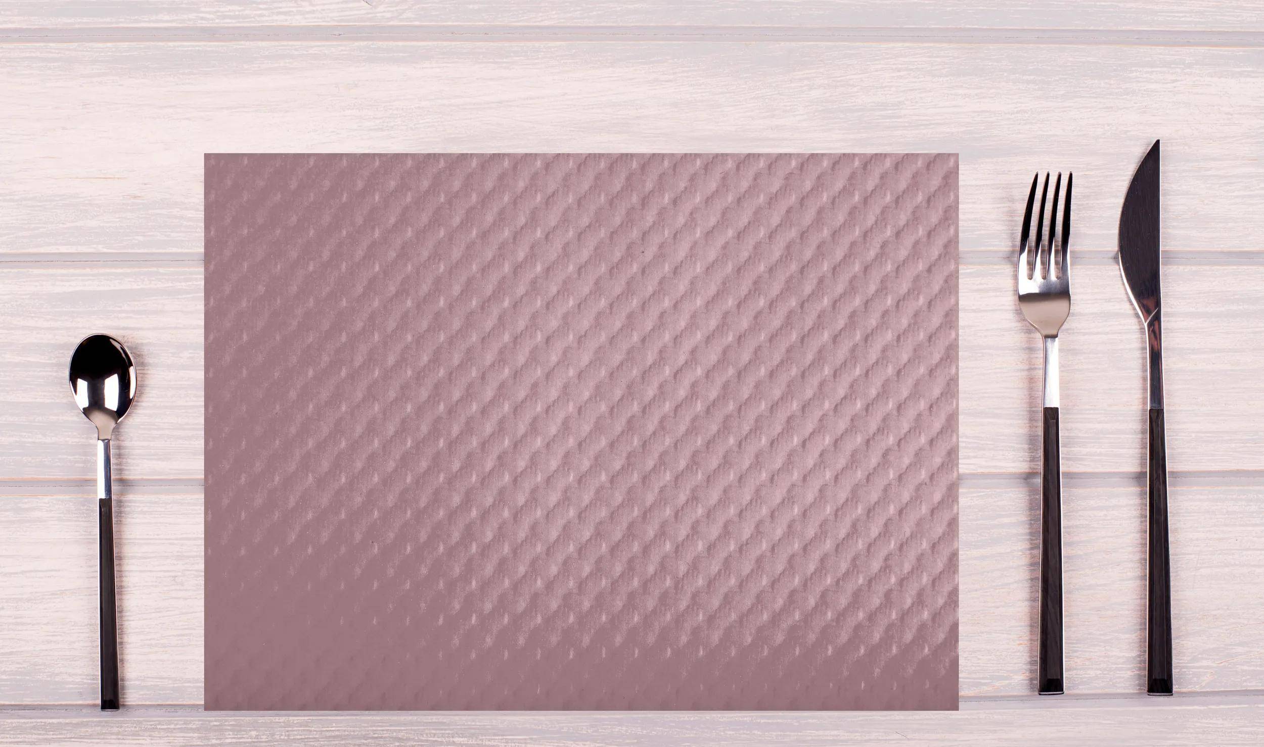Ein rosa strukturierter Hintergrund mit einem Muster aus erhabenen Diagonallinien, umrahmt von einer blassen Holzoberfläche auf drei Seiten.