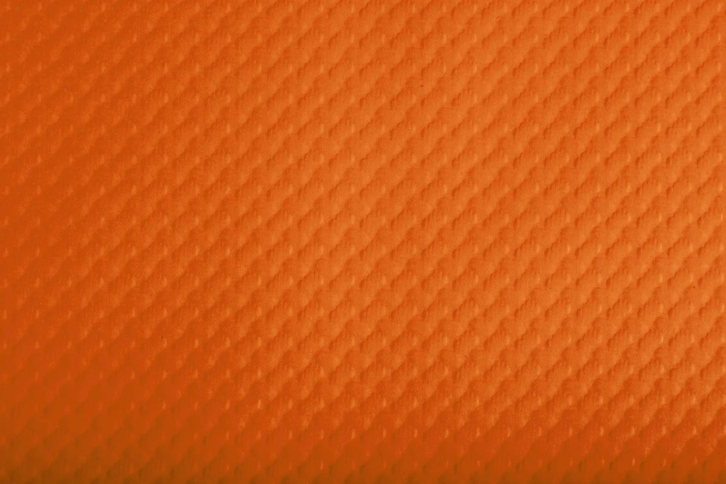 Eine orangefarbene strukturierte Oberfläche mit einem subtilen diagonalen Muster.