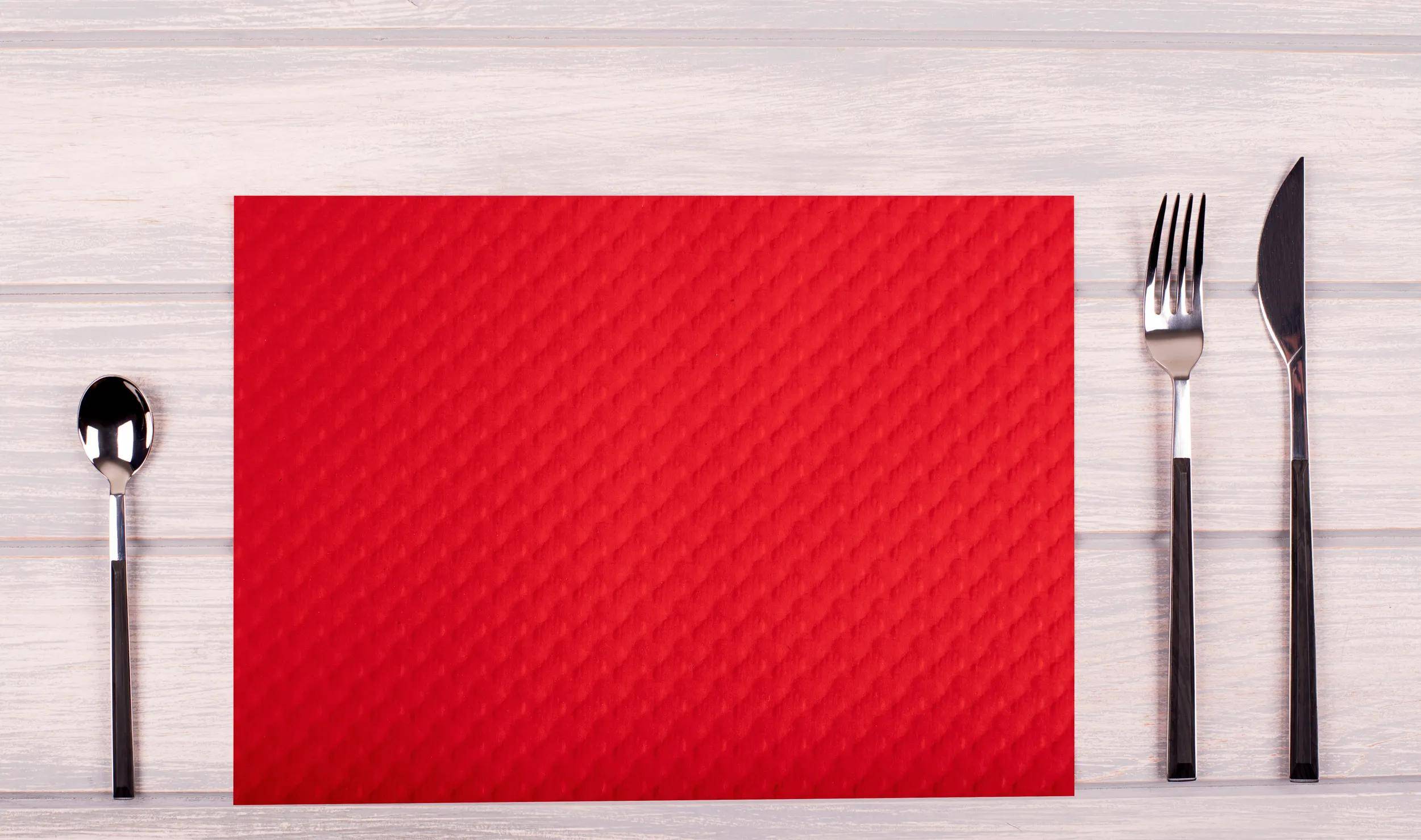 Eine strukturierte rote Oberfläche mit einem subtilen Webmuster, auf einem hellen Holzhintergrund platziert.
