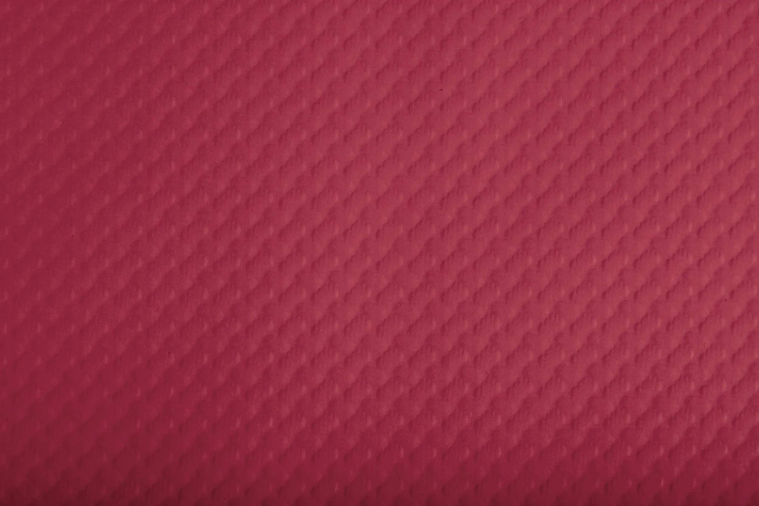 Eine strukturierte rosafarbene Oberfläche mit einem Diamantmuster, die einen subtilen, dekorativen Hintergrund bietet.