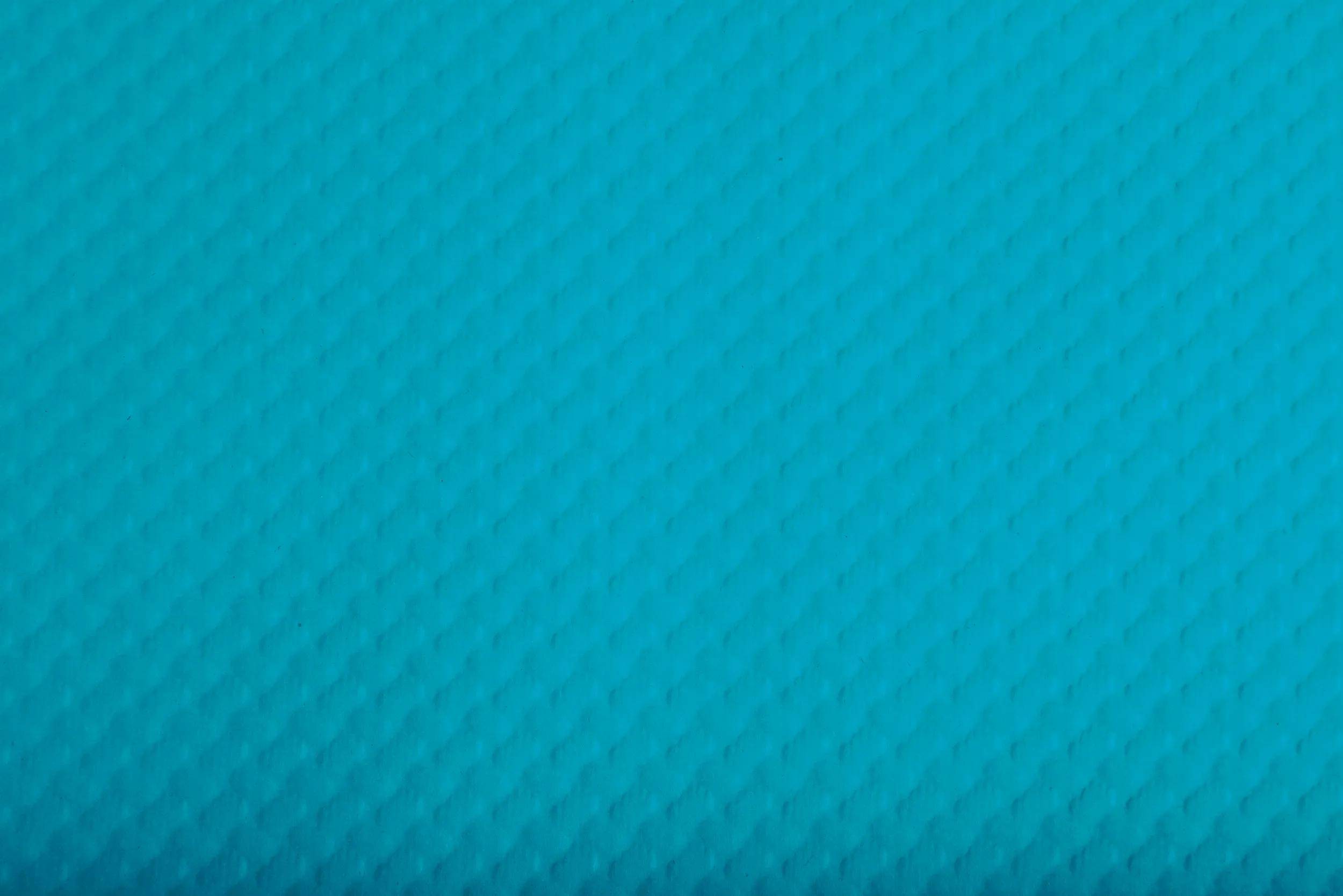 Eine Nahaufnahme einer strukturierten, hellblauen Oberfläche mit einem subtilen Rautenmuster.