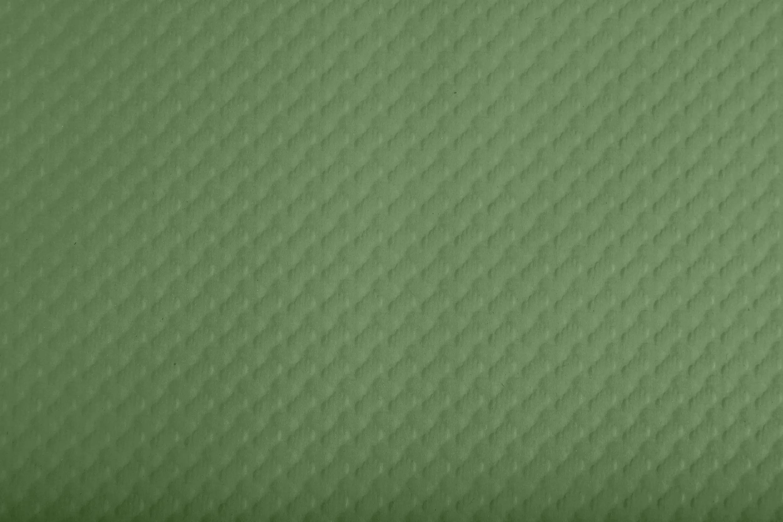 Grüne strukturierte Oberfläche mit einem diagonalen Muster aus erhabenen, diamantförmigen Rippen.