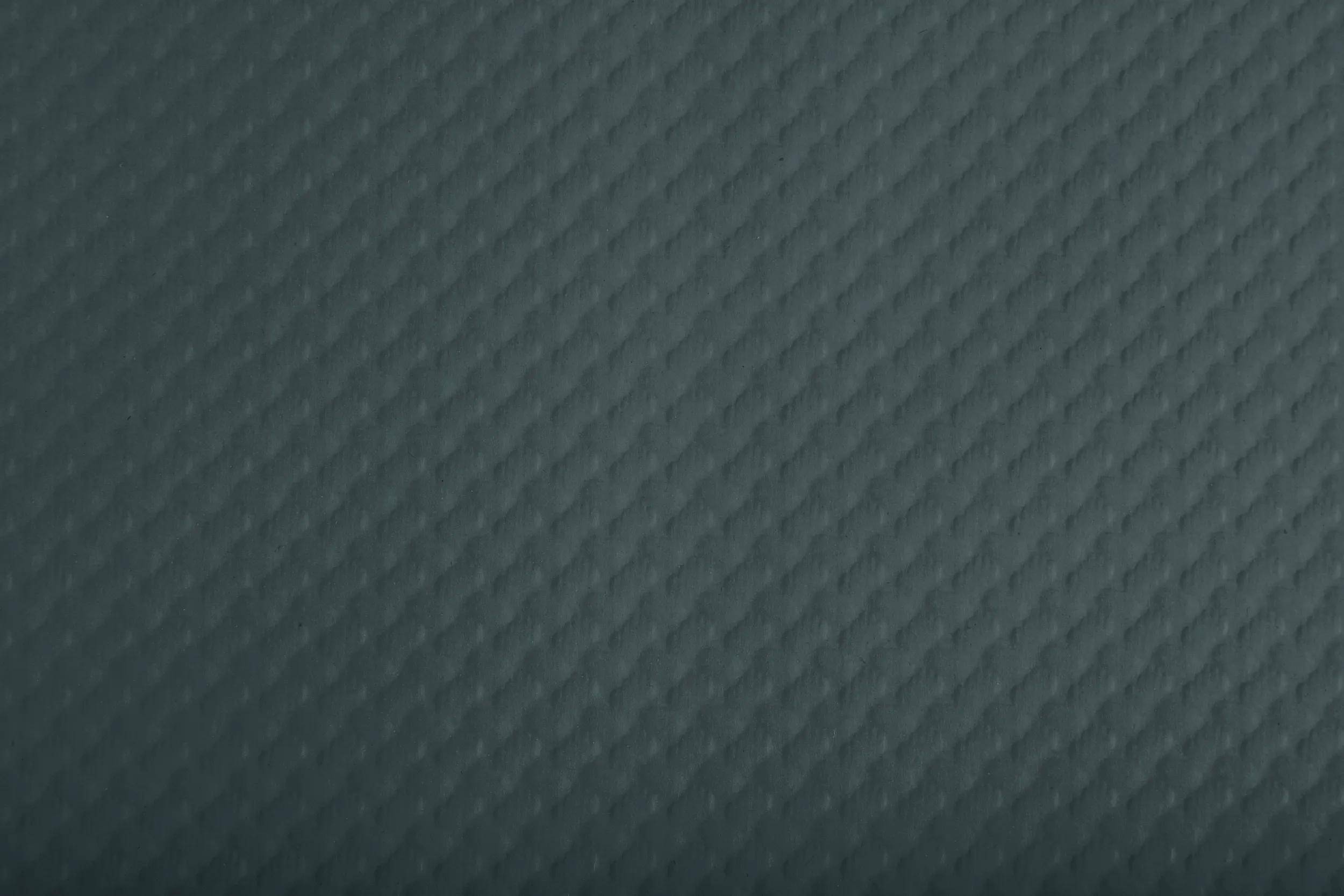 Eine strukturierte Oberfläche mit einem sich wiederholenden Rautenmuster in dunklem Grau, das ein Gefühl von Tiefe und subtiles visuelles Interesse erzeugt.