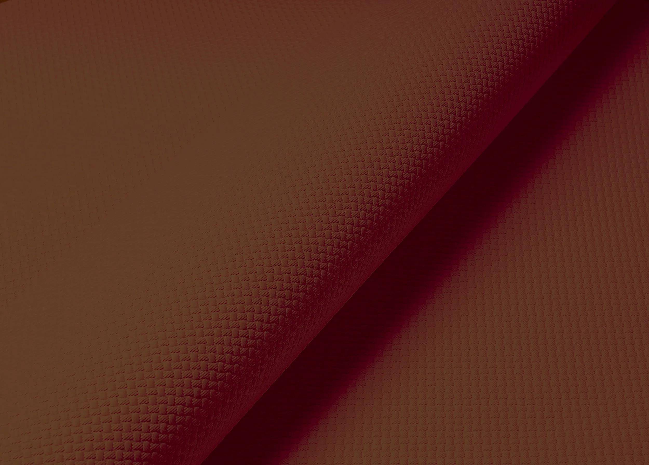 Nahaufnahme eines kastanienbraun gefärbten strukturierten Stoffes, gefaltet, um eine diagonale Naht zu zeigen, die das Muster und die Stichdetails hervorhebt.