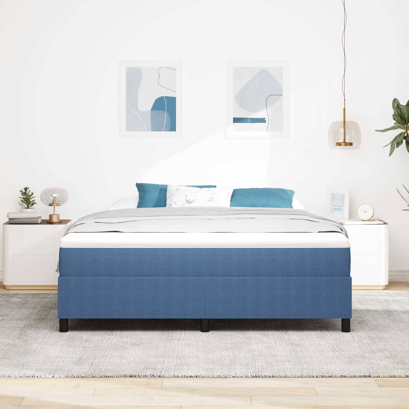 Kingsize-Bett mit blauem Bettrahmen, flankiert von zwei kleinen weißen Nachttischen. Kunstwerke und eine Pendelleuchte hängen über dem Bett.