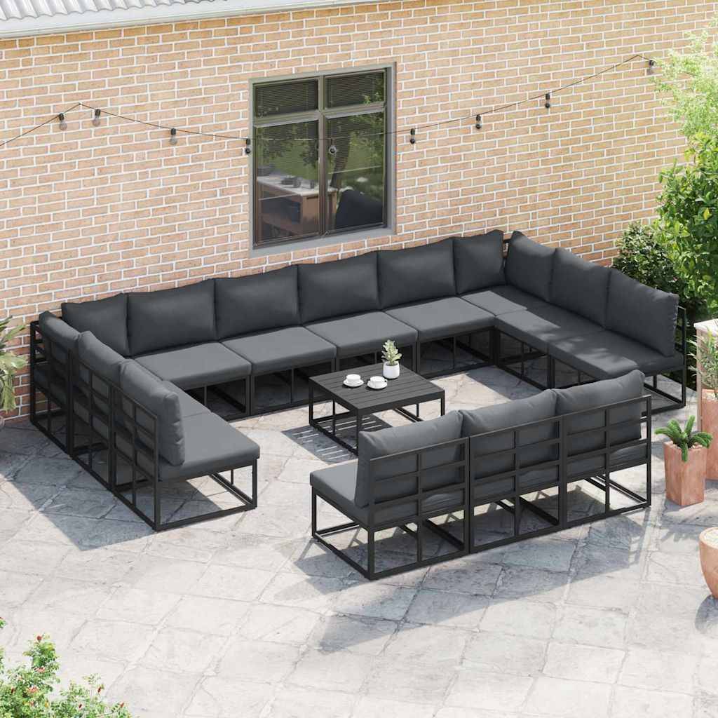 Außenbereich mit einem großen, U-förmigen grauen Ecksofa und zwei kleinen schwarzen Couchtischen auf einer Terrasse. Ziegelwand mit Fenstern im Hintergrund.
