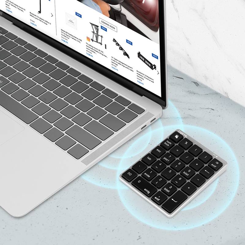 Ein Laptop mit einer externen numerischen Tastatur auf einer Marmoroberfläche; auf dem Bildschirm ist eine Website zu sehen, die Computeraccessoires präsentiert.
