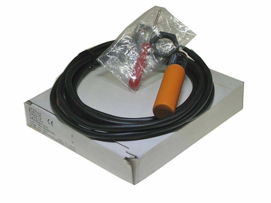 Ein aufgerollte schwarze Kabel mit orangefarbenen und schwarzen Steckverbindern in einer weißen Schachtel, obenauf ein kleiner Beutel mit Metallbefestigungen.