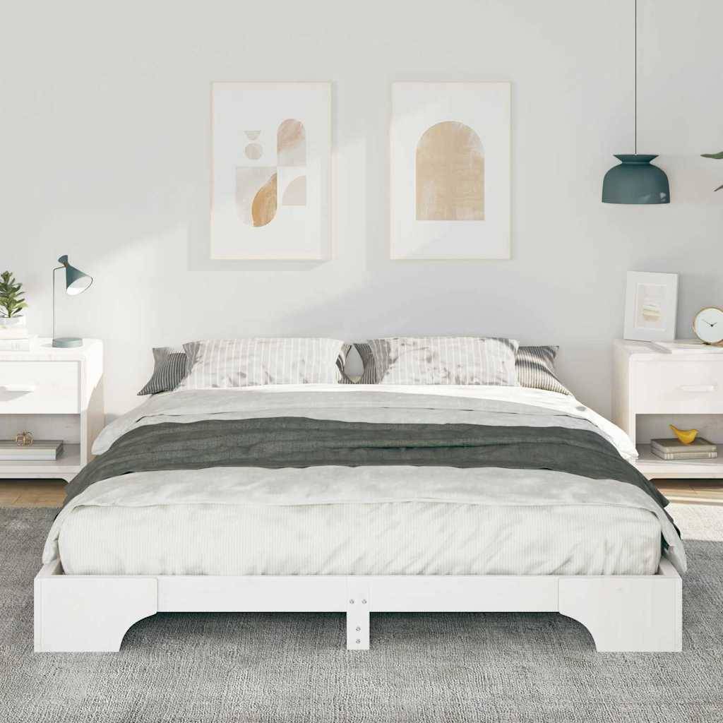 Ein modernes Schlafzimmer mit einem weißen Doppelbett, grauen Bettwäsche, zwei Nachttischen mit Lampen und abstrakten Kunstwerken an einer hellgrauen Wand.
