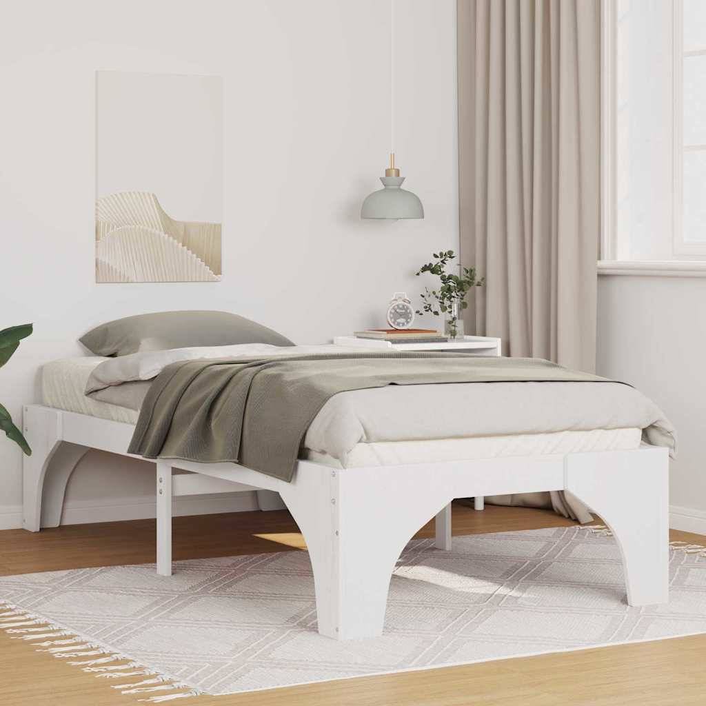 Ein modernes Schlafzimmer zeigt ein weißes Plattformbett mit beigefarbener Bettwäsche, einen Nachttisch mit Büchern und einer Lampe sowie eine hellgrüne Decke.