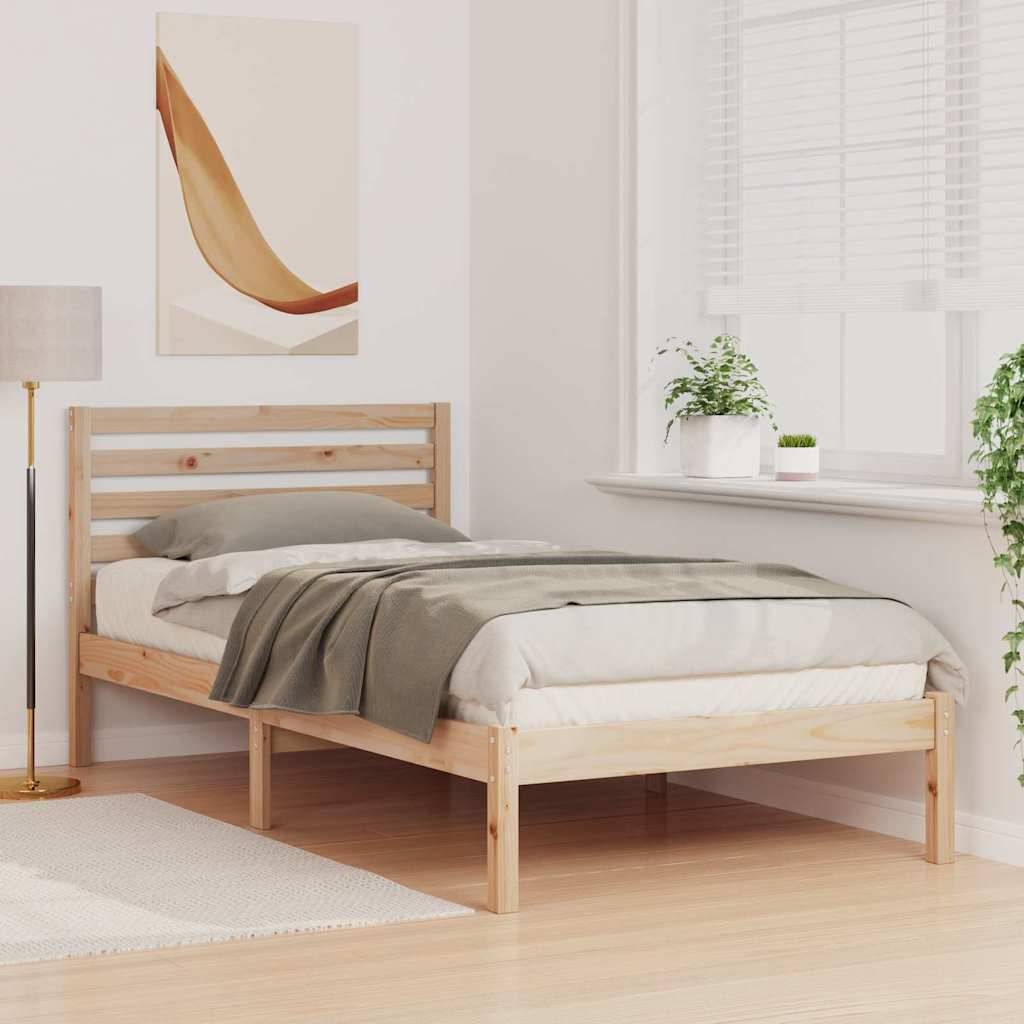 Ein minimalistisches Schlafzimmer mit einem einzelnen Holzbett, grauer Bettwäsche, einer Stehlampe, Wandkunst und Pflanzen auf einer hellen Fensterbank.