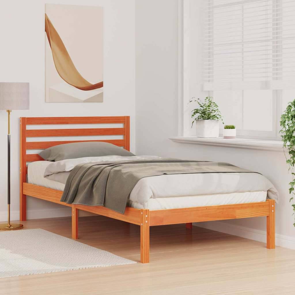 Ein gemütliches Schlafzimmer mit einem Holzbett, bezogen mit grauer Bettwäsche, einem Nachttisch mit einer Lampe, einer Pflanze auf der Fensterbank und Wandkunst.