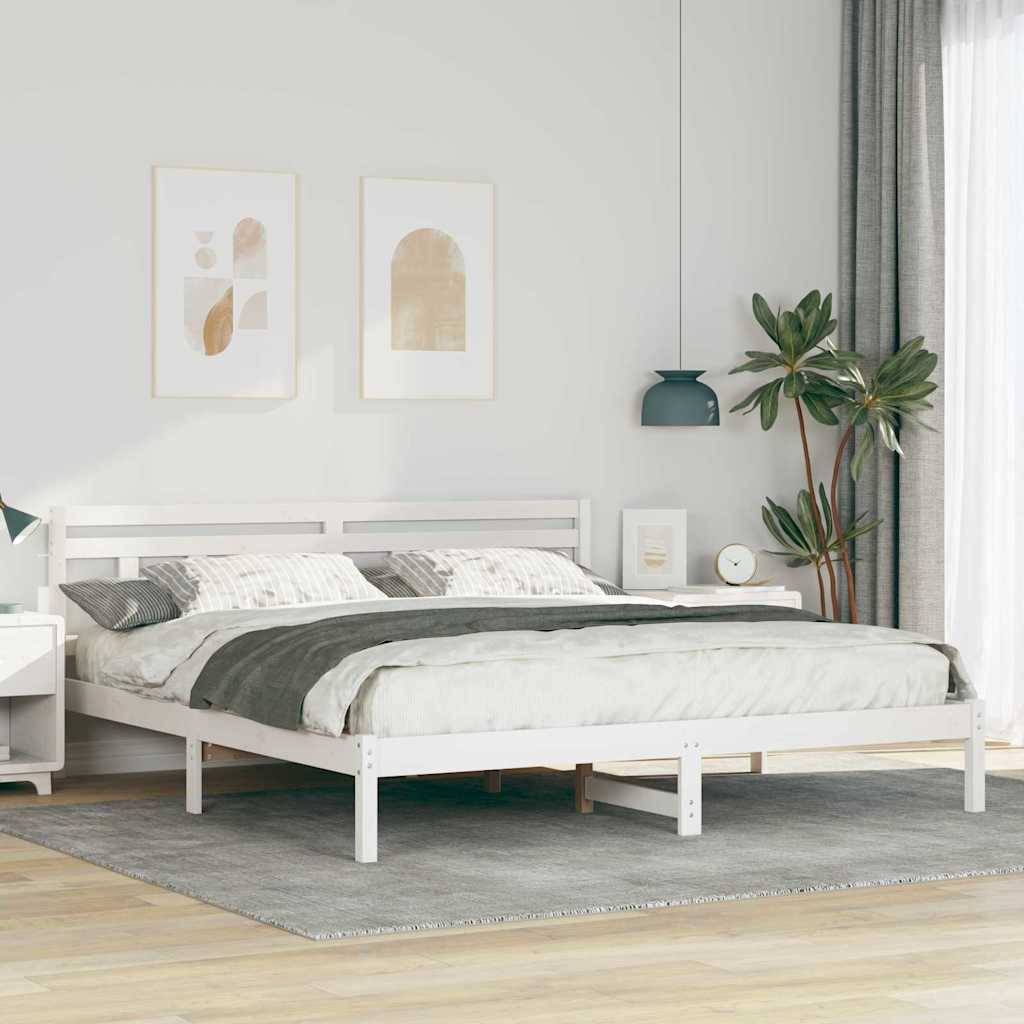 Minimales Schlafzimmer mit einem weißen Bett, grauem Teppich, gerahmten Wandbildern, einer Topfpflanze und bodenlangen Vorhängen neben einem hellen Fenster.