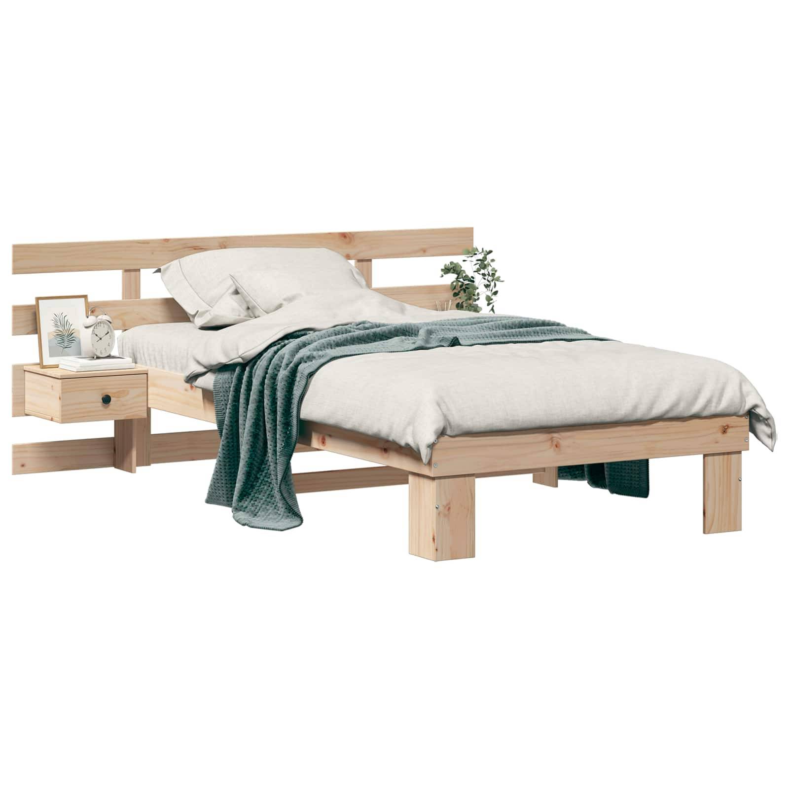 Ein Holzbett mit heller Holzoberfläche, weißer Bettwäsche, einer grünen Decke und einem kleinen angebauten Nachttisch mit Büchern und einer Pflanze.