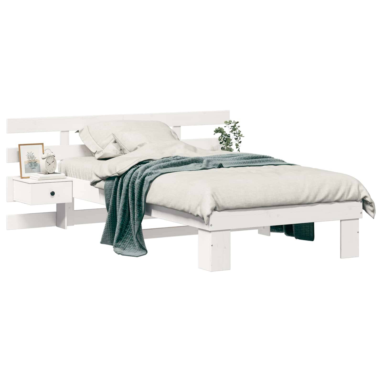 Ein modernes weißes Bett mit ordentlich arrangierten Kissen und einer grauen Decke. Ein Nachttisch trägt ein gerahmtes Bild und eine kleine Pflanze zur Dekoration.