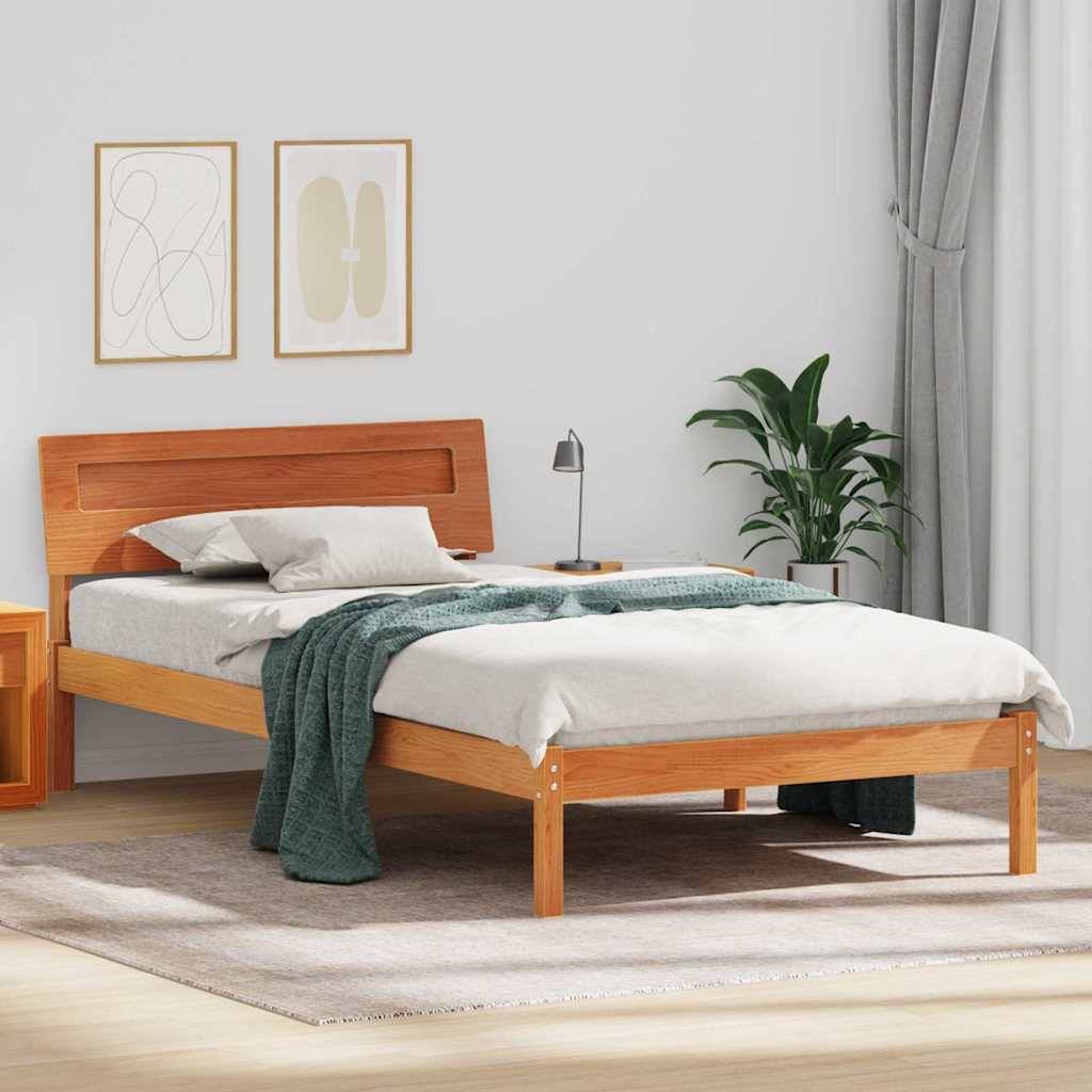 Holzbett mit weißer Bettwäsche und grüner Wurfdecke in einem minimalistischen Schlafzimmer, neben einer Pflanze, einer Lampe und gerahmter Wandkunst.