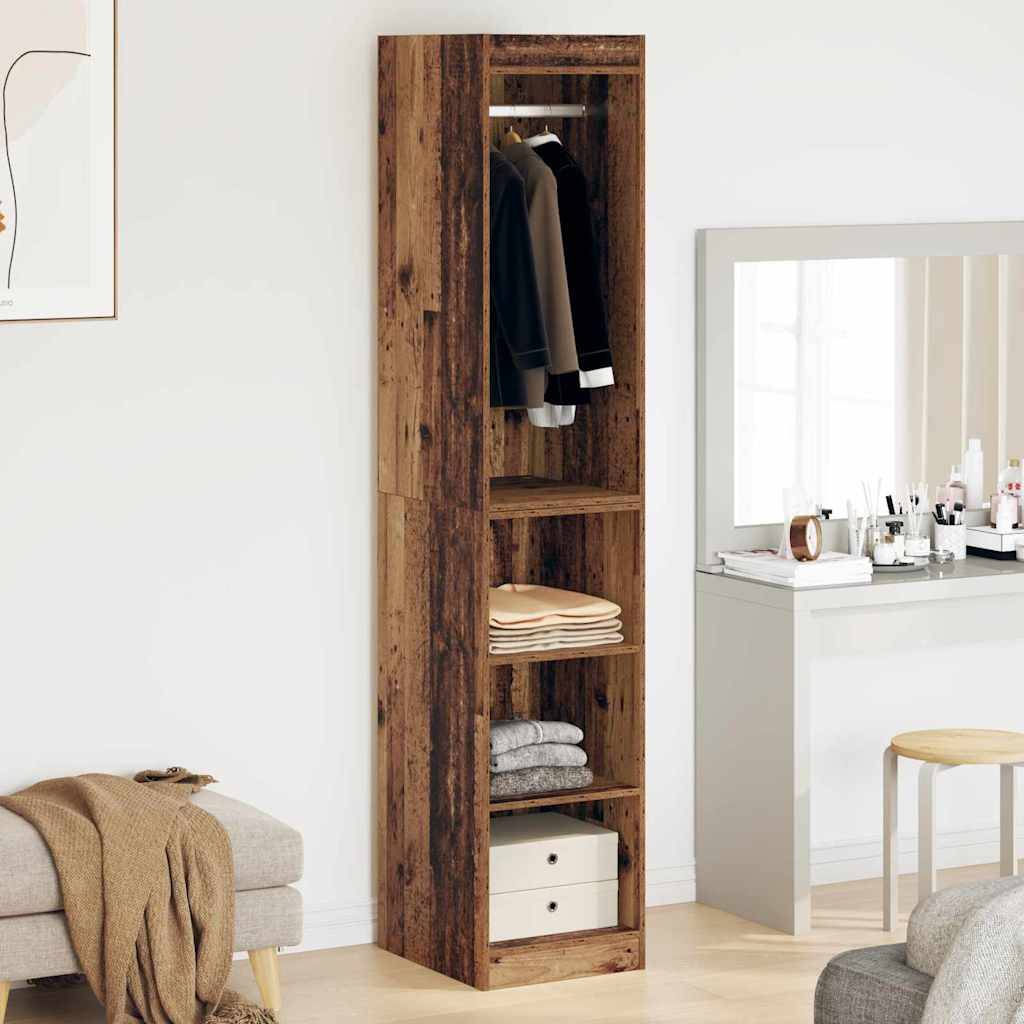 Ein Holzkleiderschrank mit Kleidung und Regalen steht neben einer schlichten weißen Anrichte mit einem großen Spiegel, zwei Hockern und dekorativen Gegenständen.