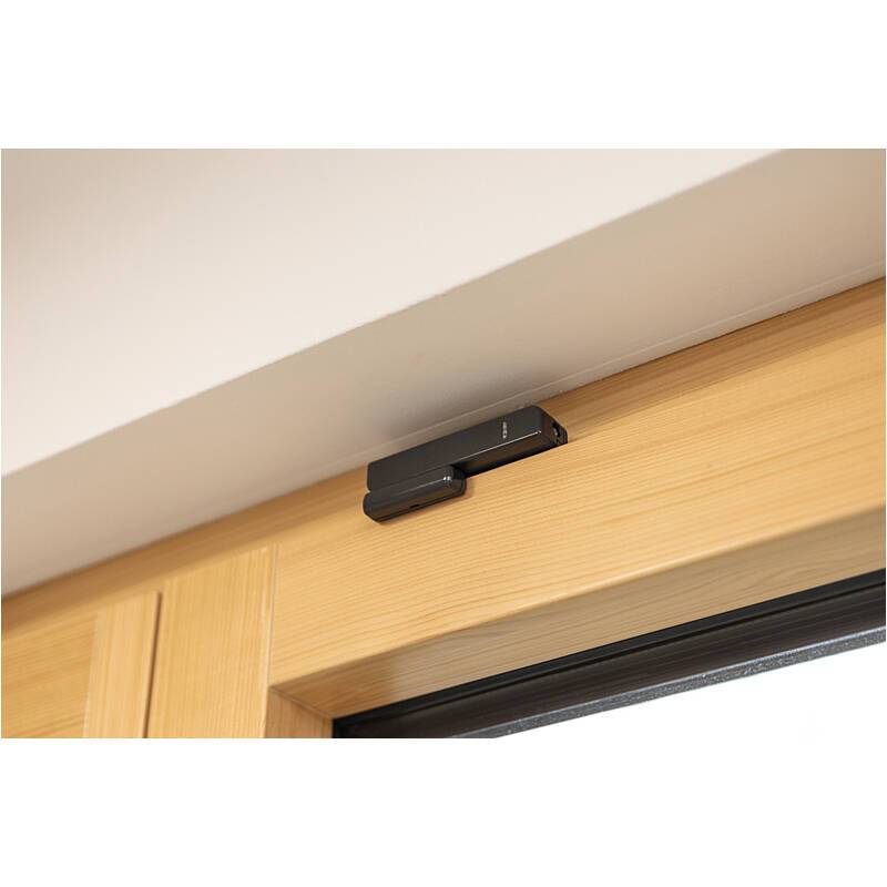 Schwarzer Türsensor, der über einem Holztürrahmen in der Nähe der Decke angebracht ist.