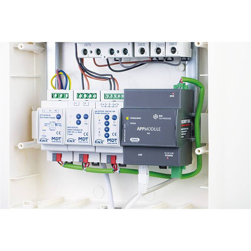 Elektrisches Schaltschrank mit KNX-Modulen und Verkabelung in einem wandmontierten Gehäuse, einschließlich einer APPMODULE-Einheit und angeschlossenen grünen Kabeln.