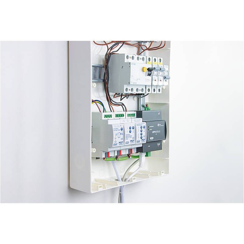 Offenes Elektroverteilerpanel mit Leistungsschaltern, Verkabelung und Steuermodulen, die in einem Wandschrank montiert sind.