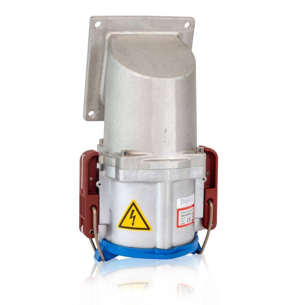 Robuster industrieller Stecker mit silbernem Gehäuse, roten und blauen Akzenten und einem gelben Warnsymbol, der vertikal an einem Wandhalter montiert ist.