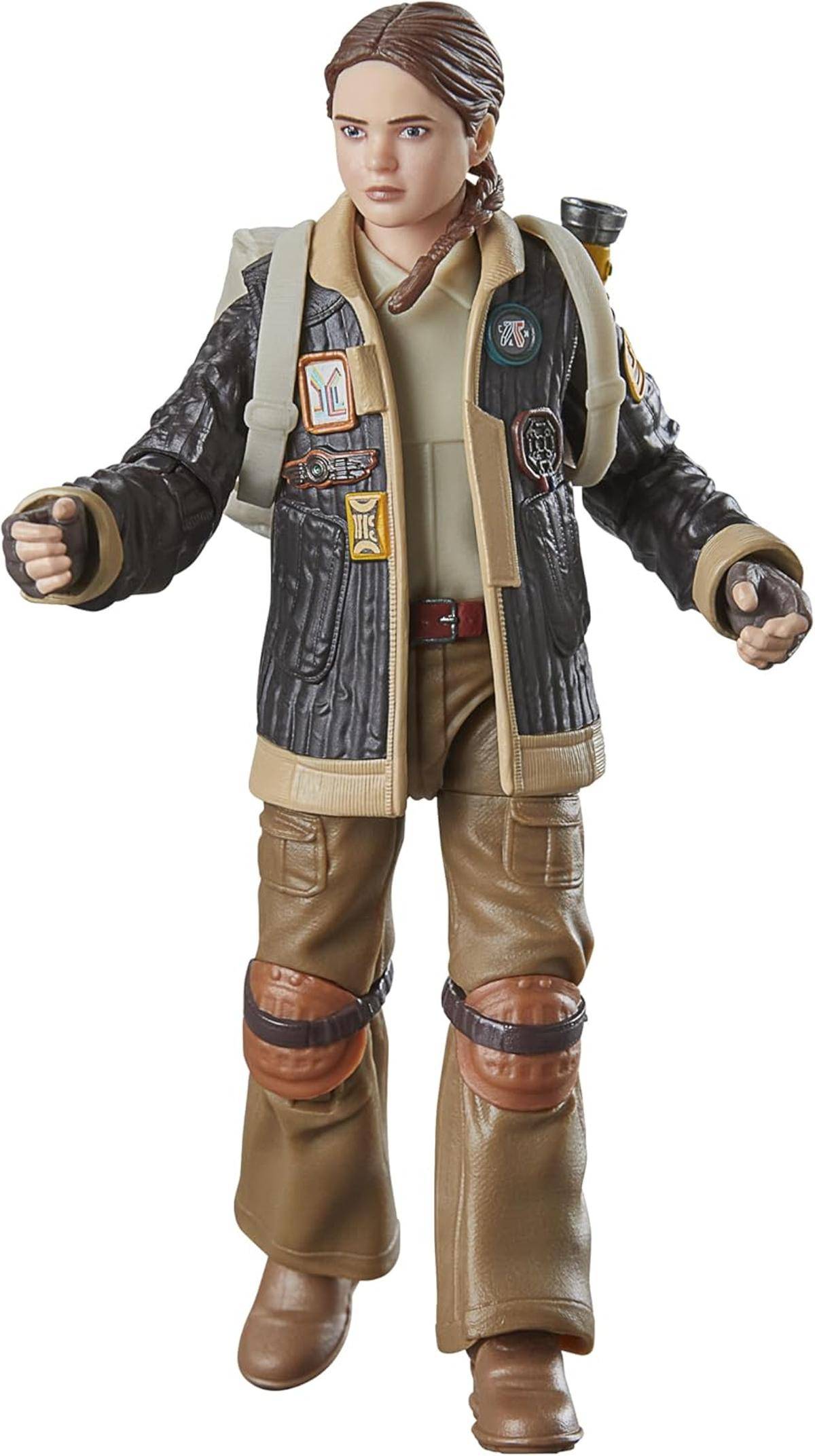 Eine stehende Actionfigur einer jungen Frau in einem braun-schwarzen Outfit, die eine beige Weste und Cargohosen trägt.