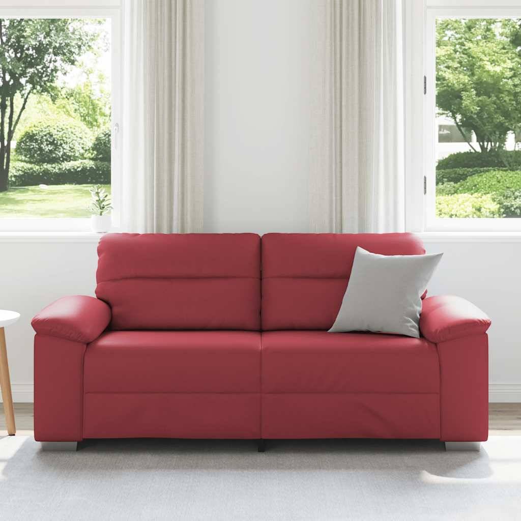 Ein rotes Sofa mit einem grauen Kissen ist in einem hellen, modernen Wohnzimmer mit großen Fenstern platziert, die einen Blick auf grüne Natur draußen zeigen.