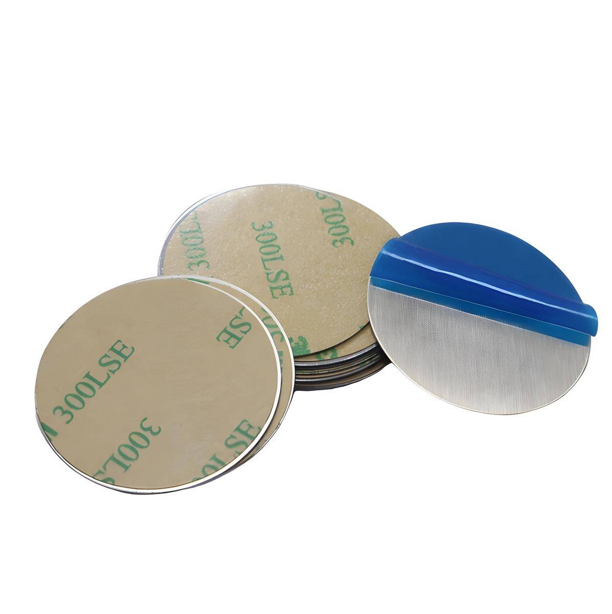 Ein Stapel runder, selbstklebender Metallscheiben mit Schutzfolie neben einem blau gehaltenen Spachtel, der zum Aufbringen oder Entfernen der Scheiben verwendet wird.