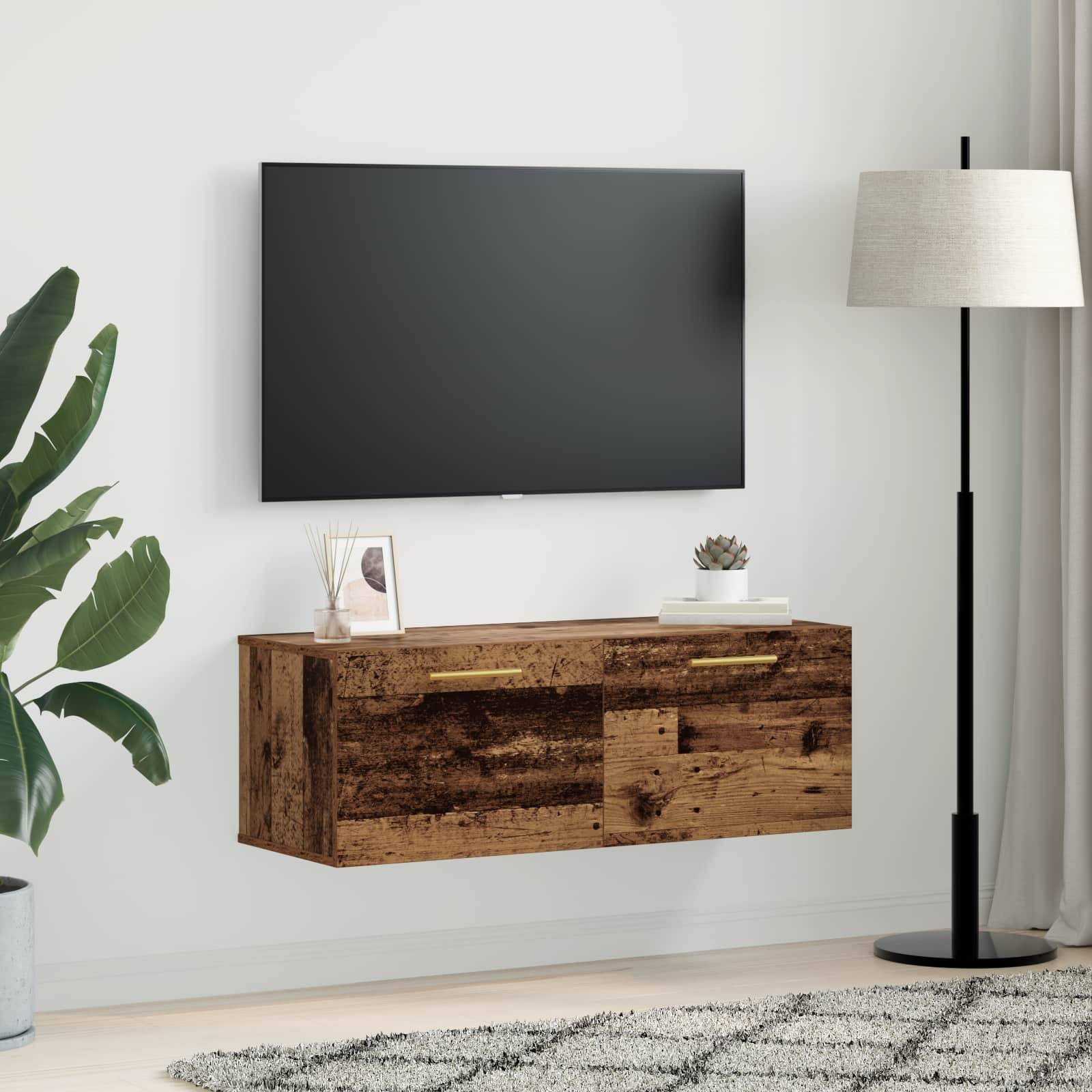 Wohnzimmer mit an der Wand montiertem Fernseher über einem rustikalen Holzschrank, neben einer Stehleuchte und einer Zimmerpflanze.