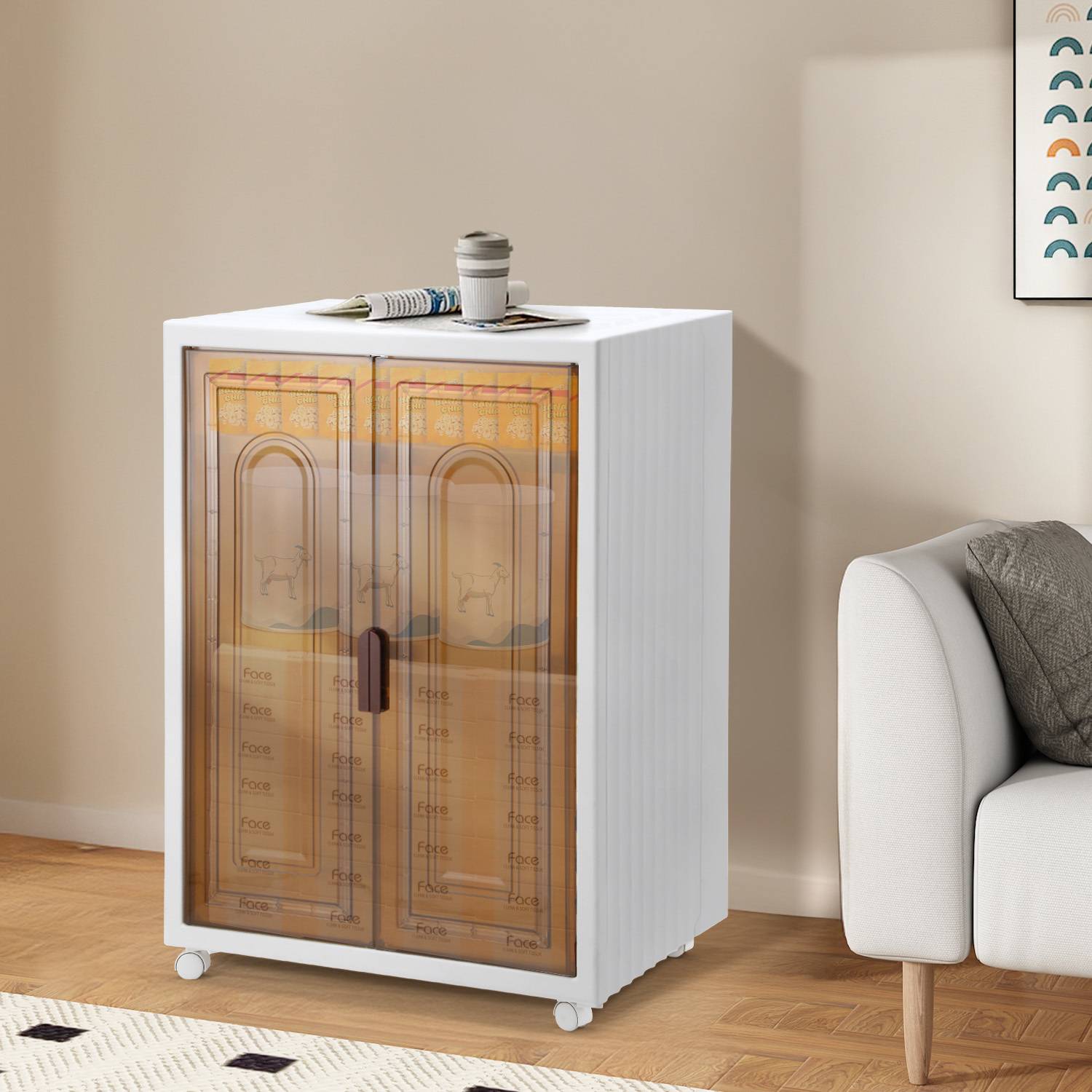 Weißer fahrbarer Schrank mit durchscheinenden bernsteinfarbenen Doppeltüren und einer Tasse obenauf neben einem Sofa im Wohnzimmer.