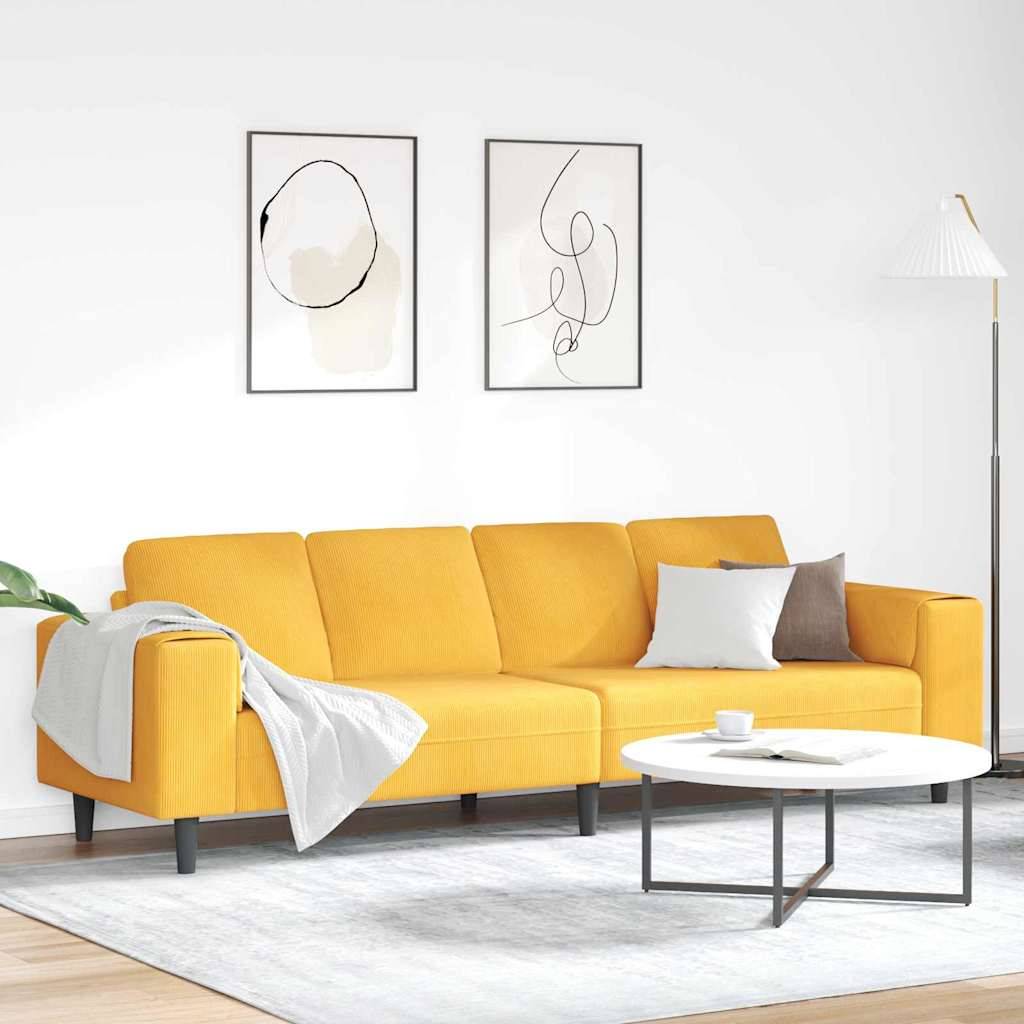 Ein modernes Wohnzimmer mit einem gelben Sofa, das mit einer Decke bedeckt ist, zwei abstrakten Kunstwerken an der Wand und einem runden Couchtisch auf einem hellen Teppich.