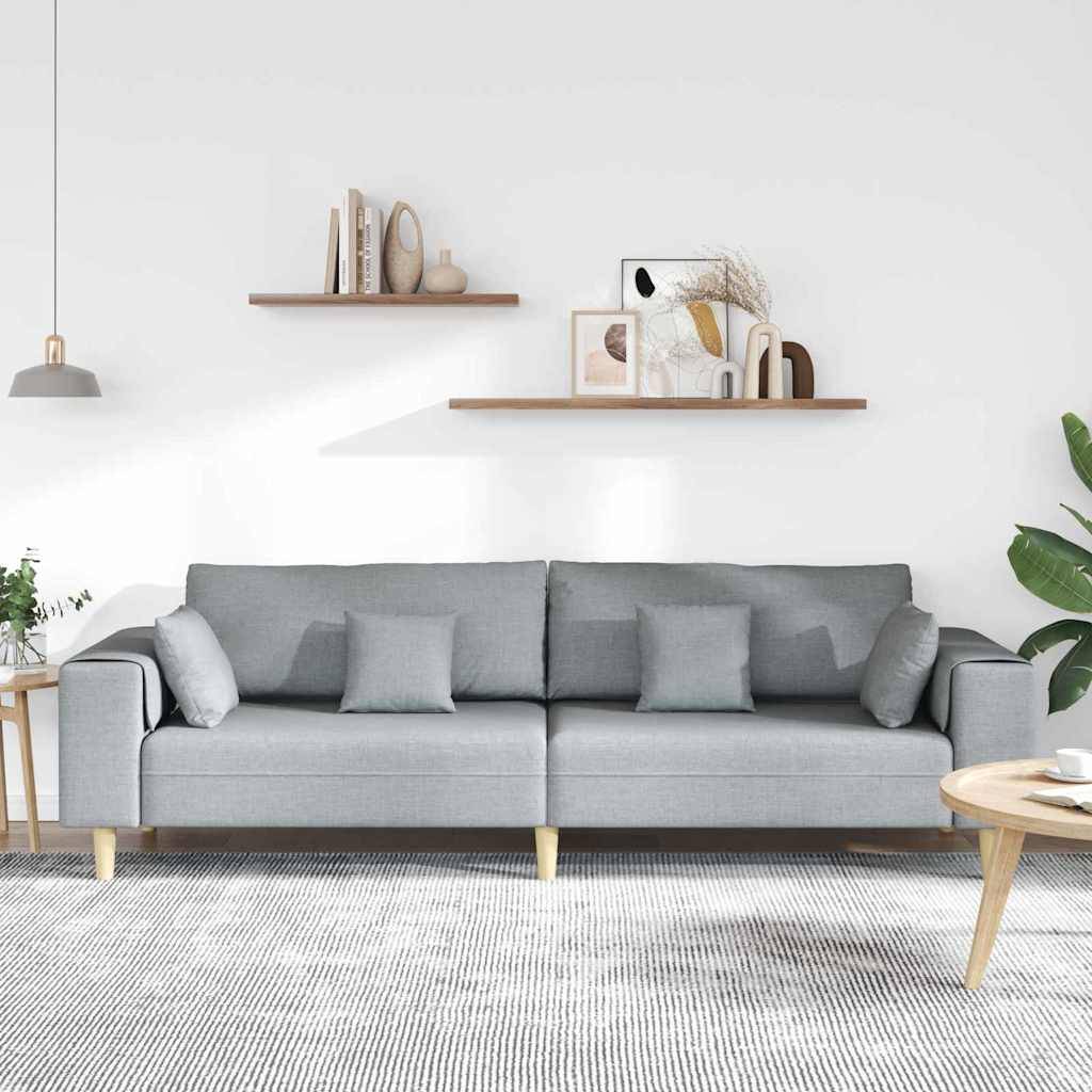 Ein modernes Wohnzimmer mit einem grauen Sofa, dekorativen Kissen, zwei Holzregalen mit Büchern, Pflanzen und Kunstwerken sowie einem runden Holzcouchtisch.