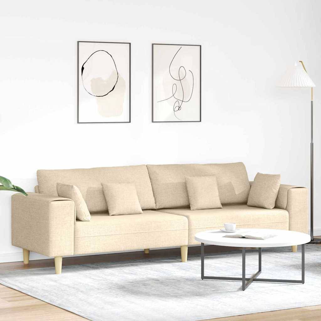 Ein beige Sofa mit mehreren Kissen steht in einem modernen Wohnzimmer. Zwei abstrakte Kunstwerke hängen darüber. Ein runder Couchtisch und eine hohe Stehlampe befinden sich in der Nähe.